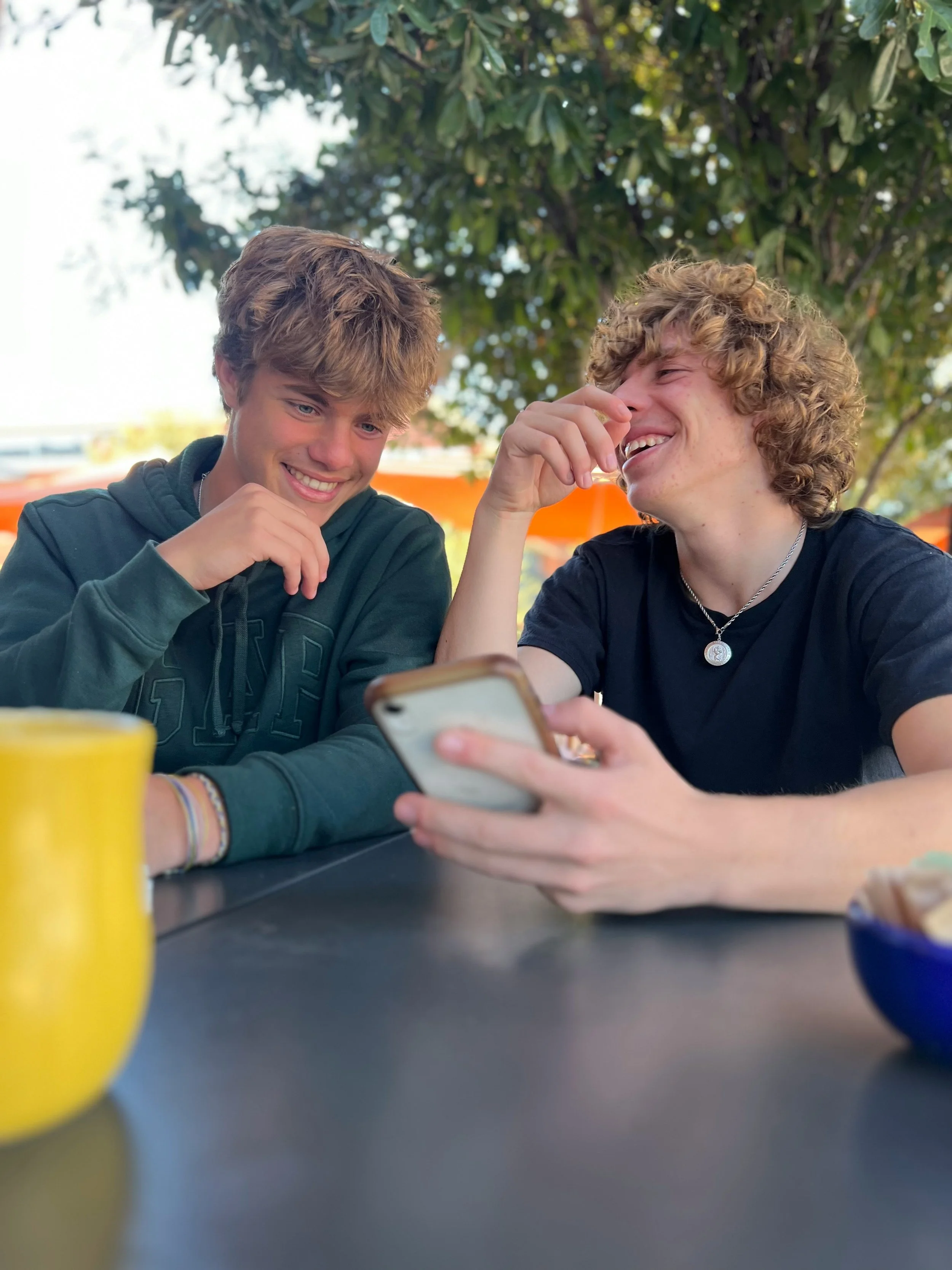 Two teenage boys laughing with a phone