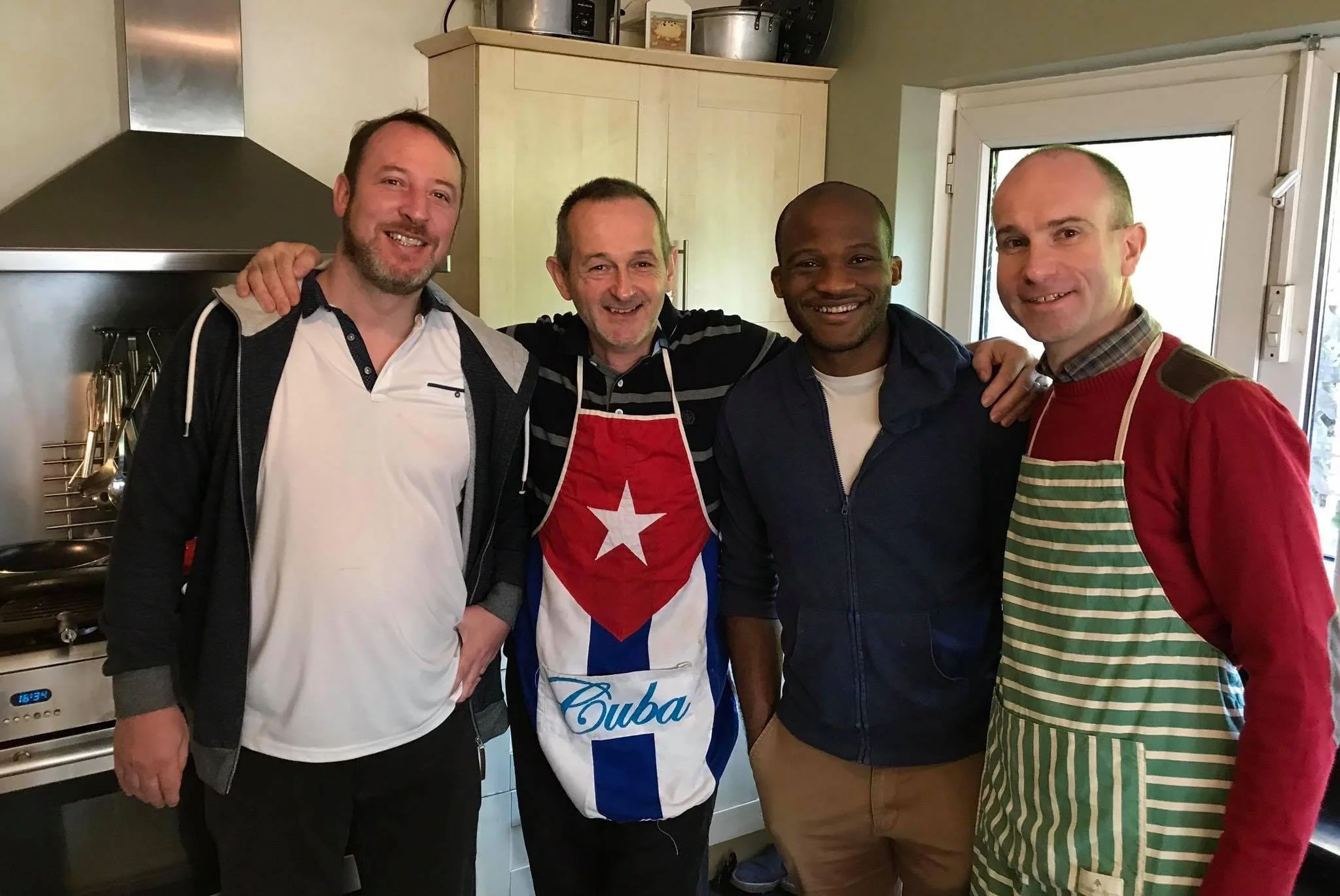 Four men pose together with aprons on as they cook up a storm for their connect group