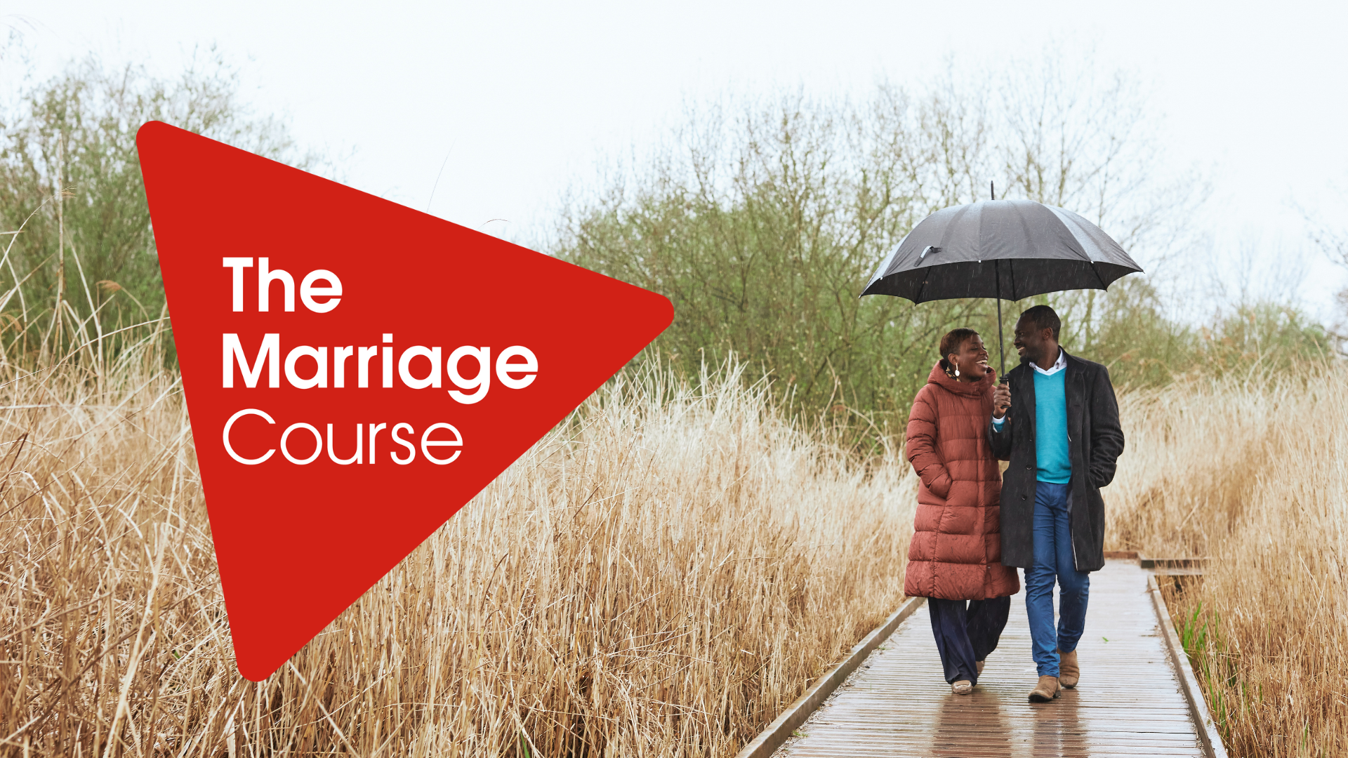 A couple stand under an umbrella in a field in Caerphilly