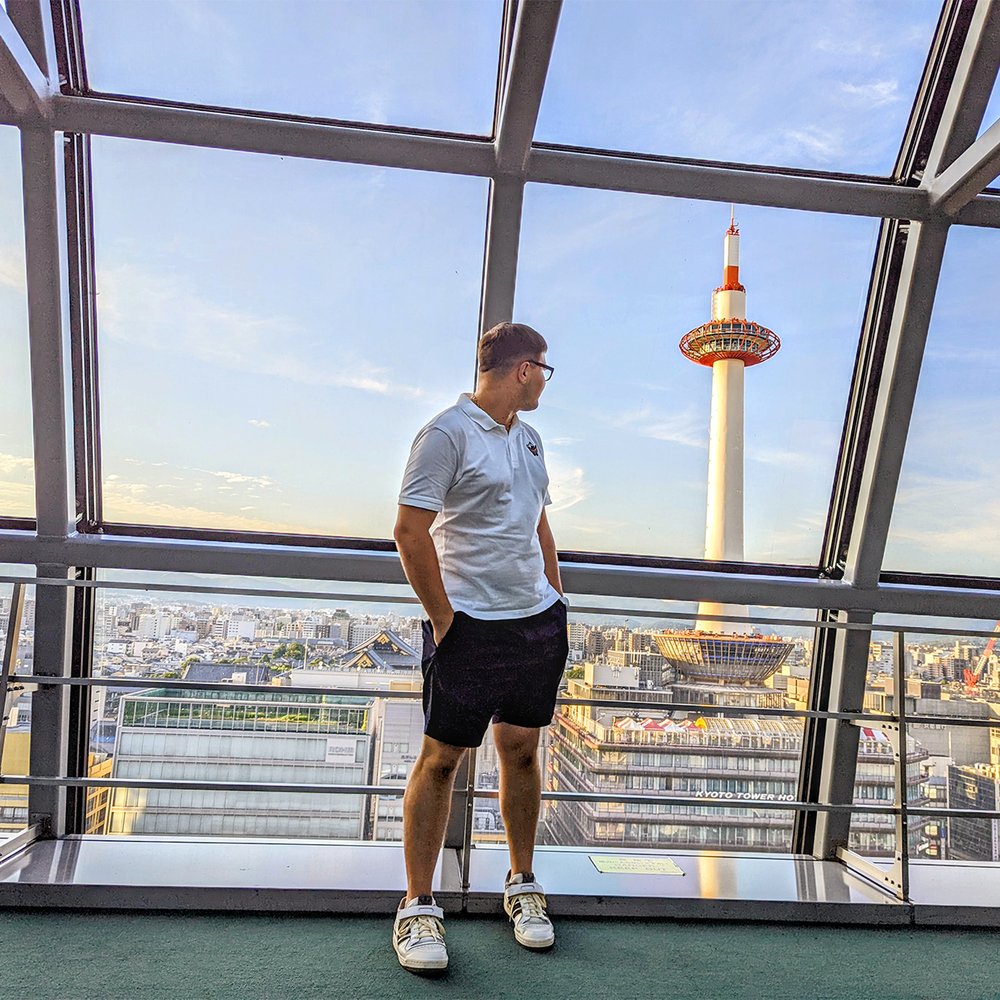  Posing in Kyoto Station’s skyway with Kyoto Tower in the distance, Kyoto, Japan (2022). 