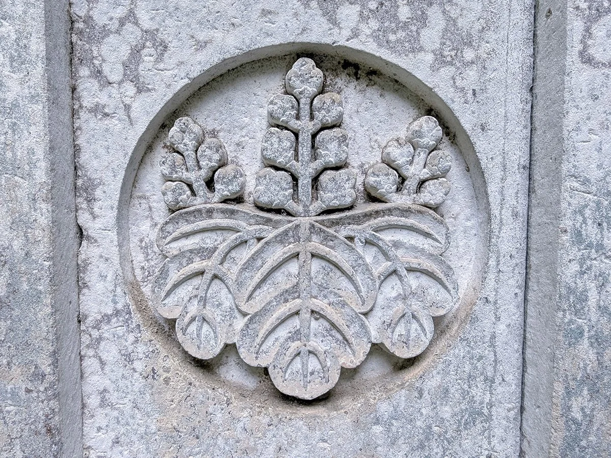 Goshichikiri (paulownia) crest of the Toyotomi family carved in Shakudani stone at Senjojiki Cemetery (千畳敷), Daianzenji Temple (大安禅寺), Fukui City, Fukui Prefecture, Japan (2026). Photo by Danny With Love.