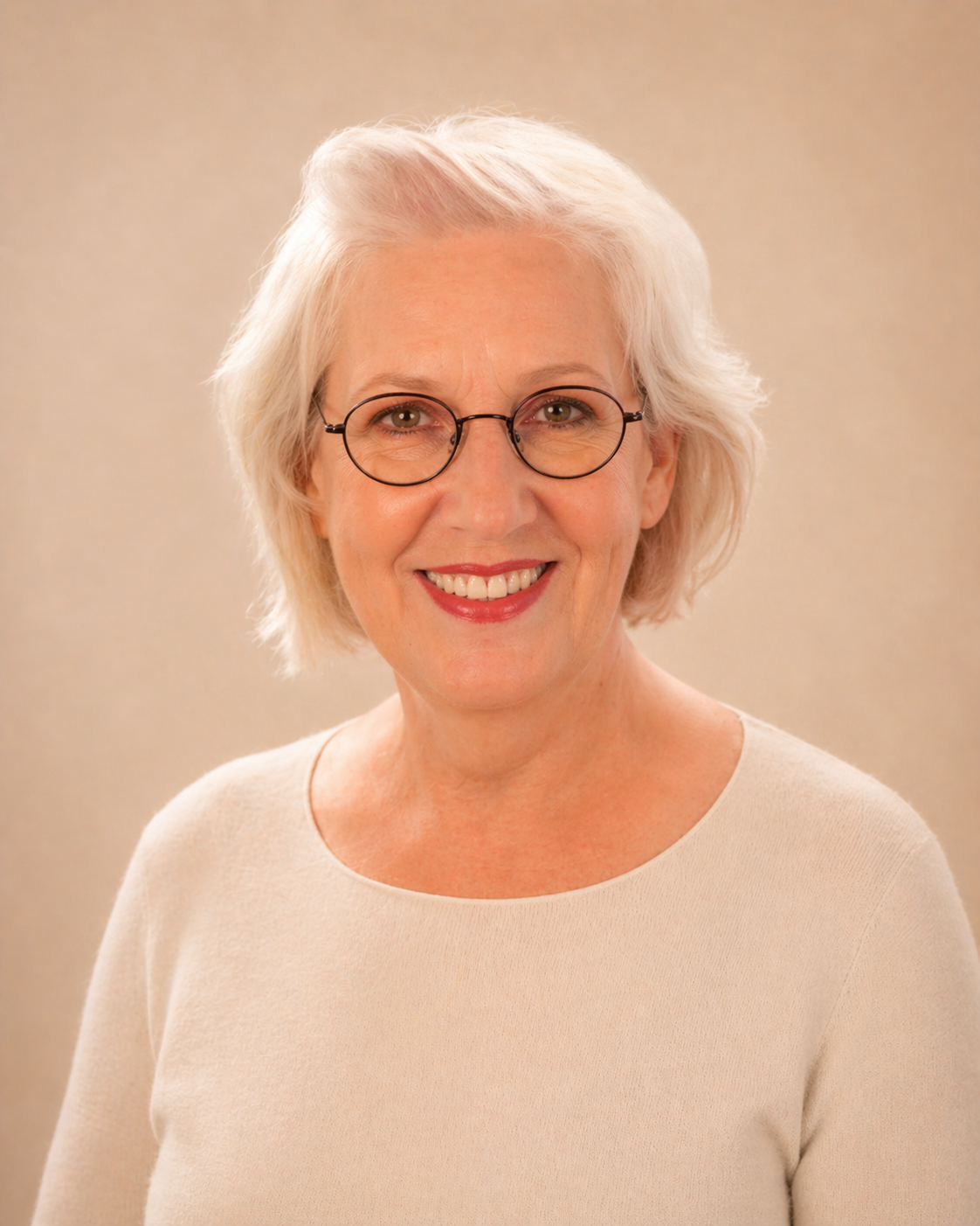 A woman with white hair and glasses smiling outdoors