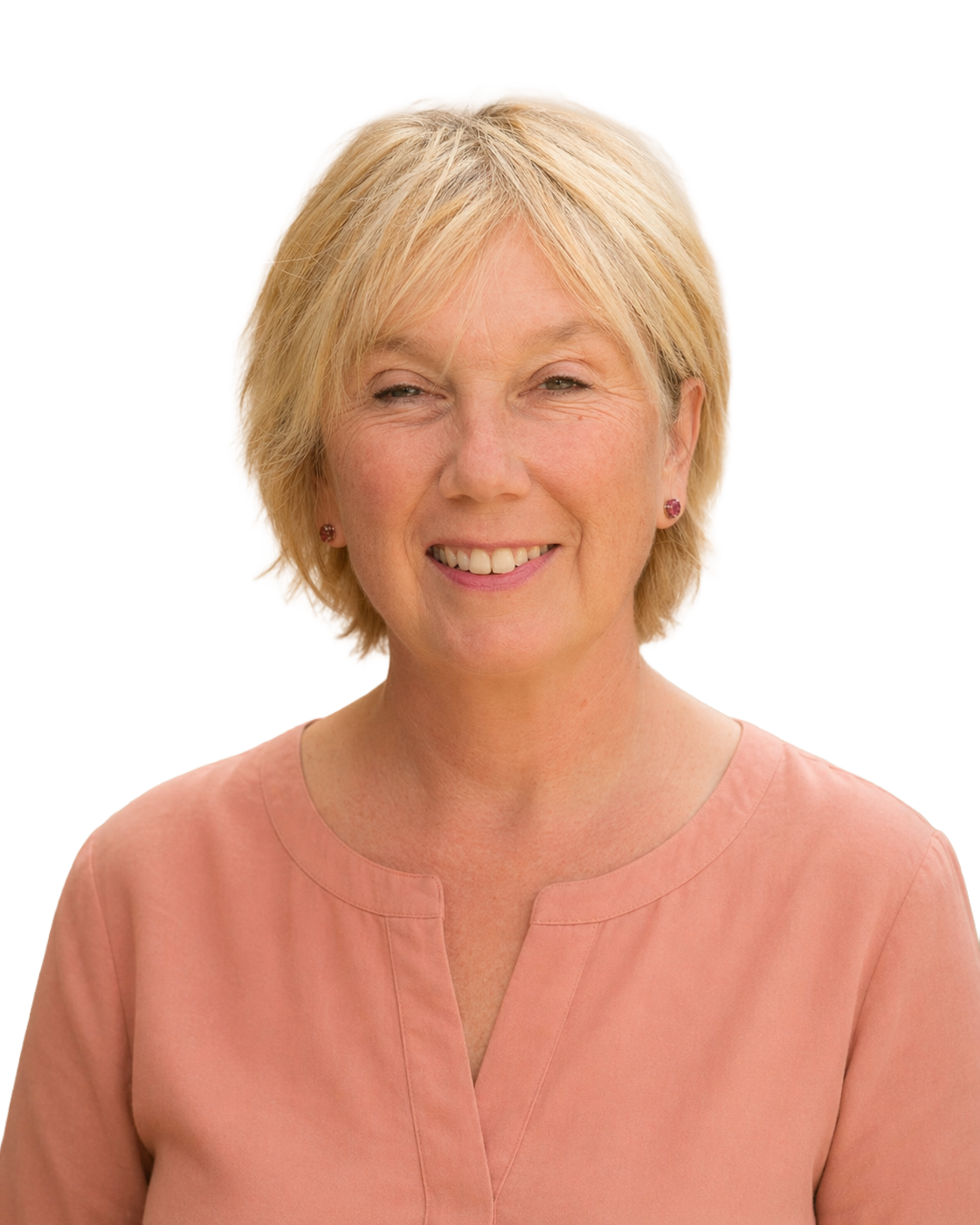 A smiling woman with blonde hair standing outdoors in a garden with pink flowers and a wooden fence in the background