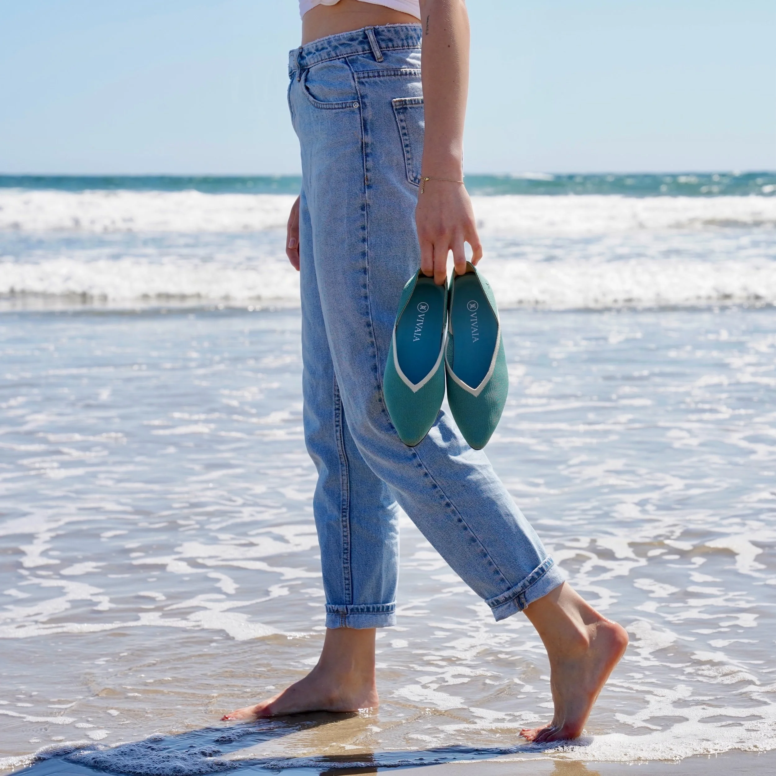 Woman walking on beach feet in water