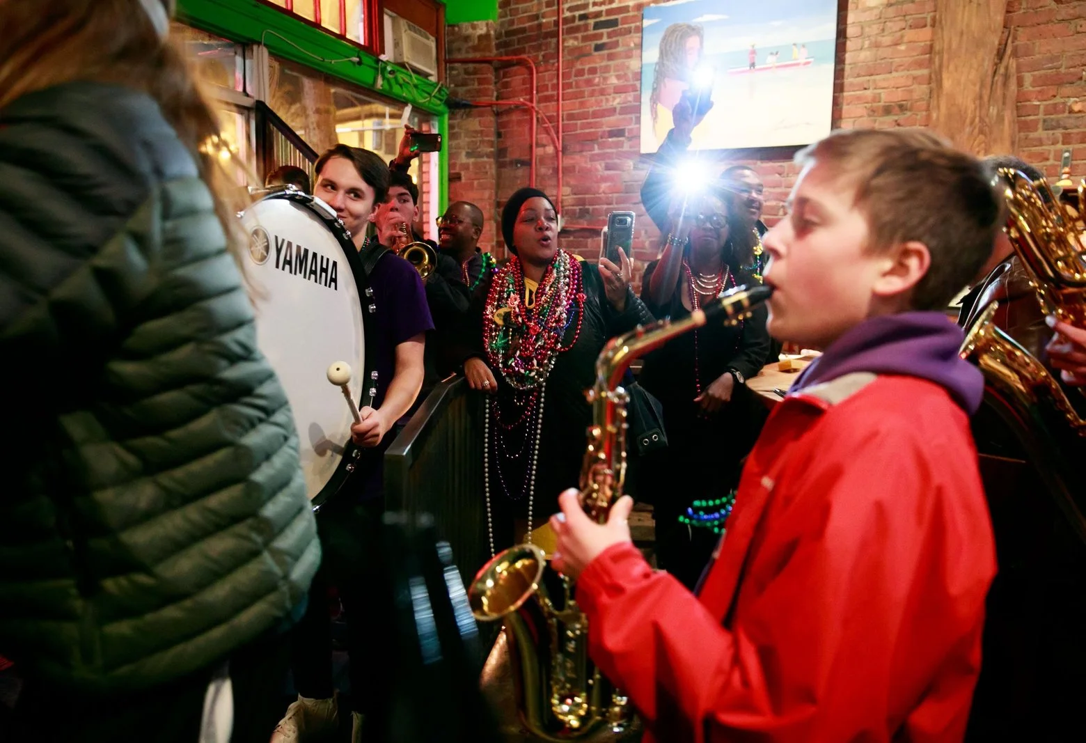 Columbia City Beatwalk lead organizer Tish Gallow, center, cheers on the Garfield High School Marching Band during 2018’s Fat Tuesday edition of the longstanding neighborhood music crawl.