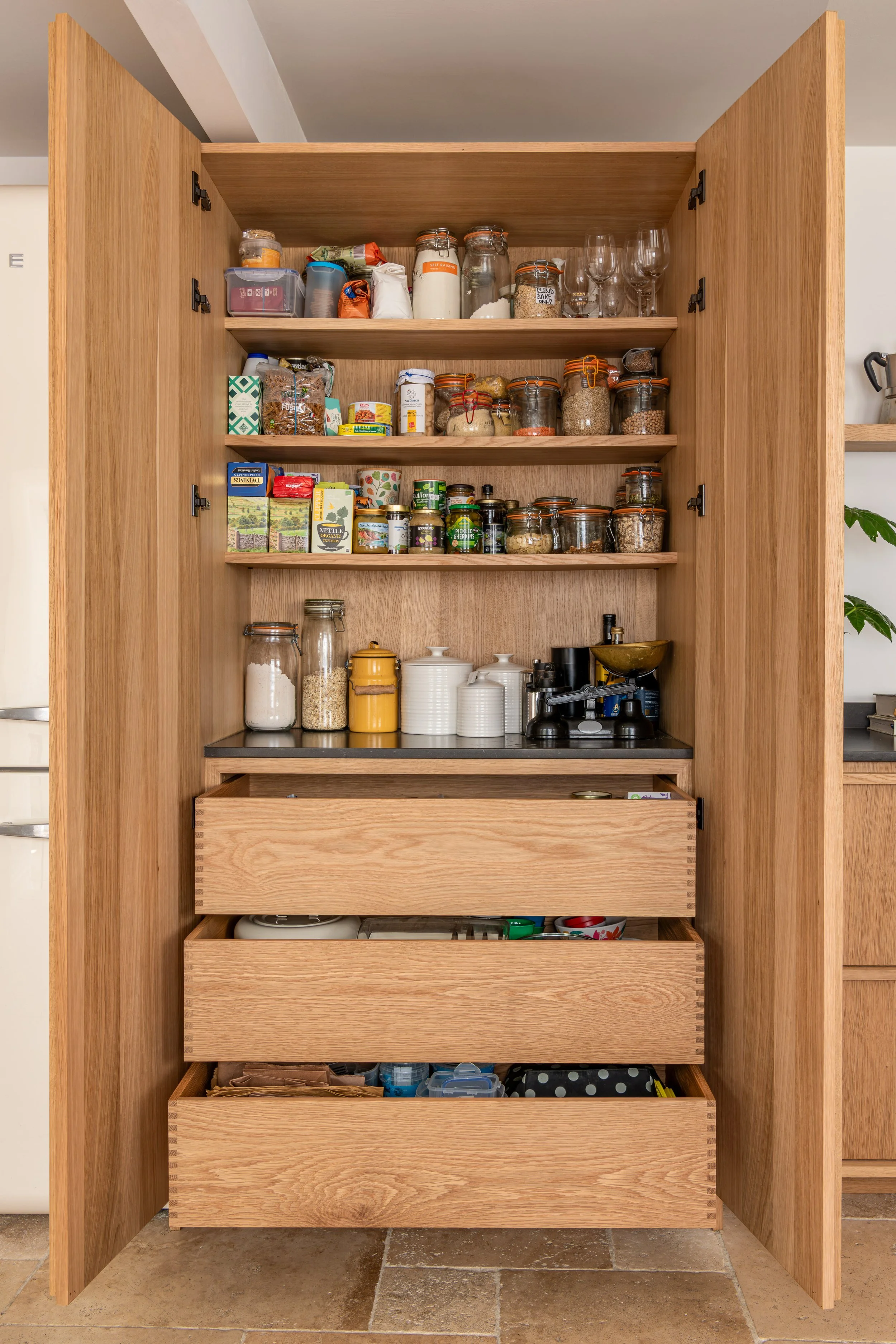 Open oak pantry cabinet with internal shelving, drawers and storage
