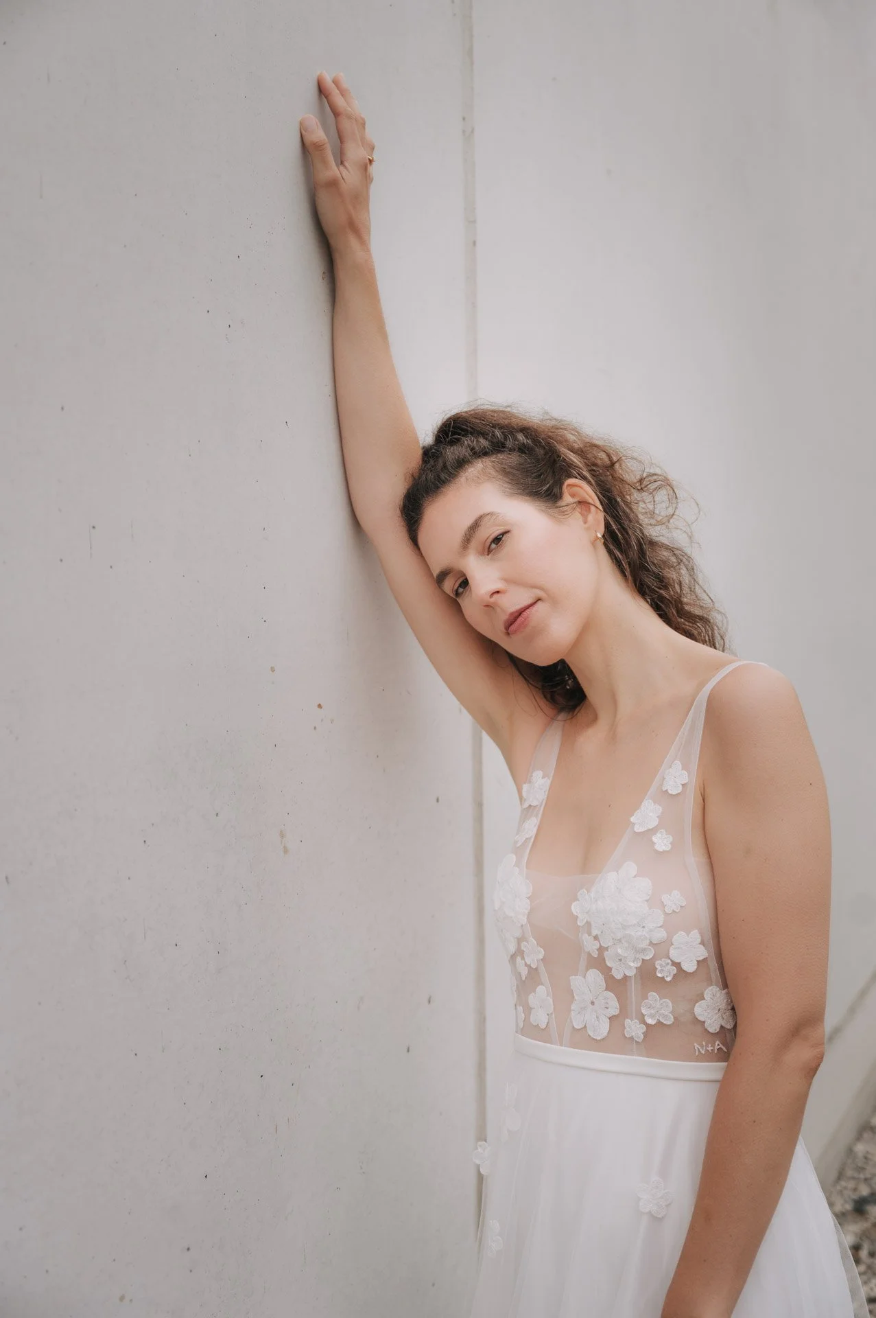 Braut lehnt mit einem Arm an der Wand