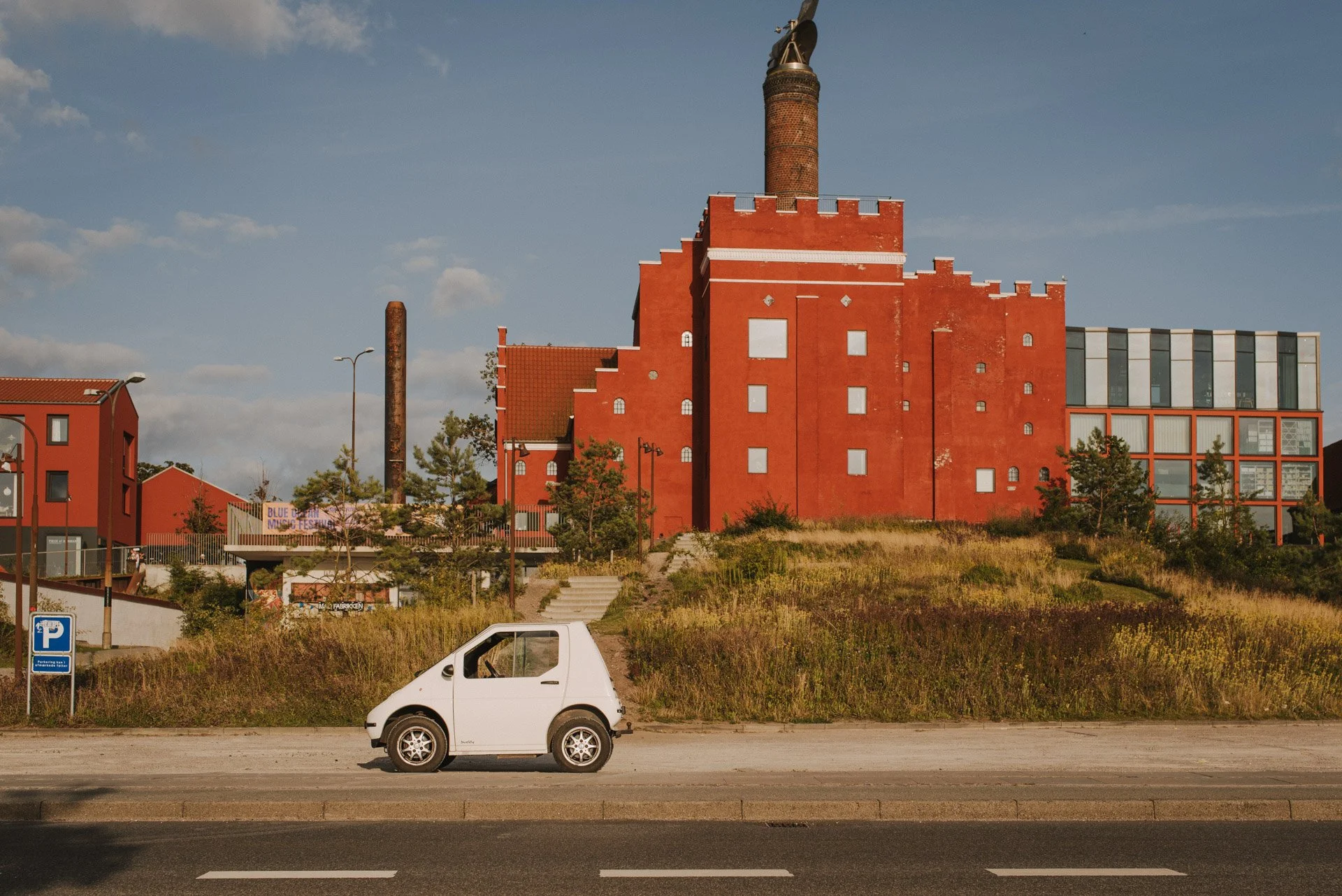 kleines weisses Auto vor rotem Fabrikgebäude