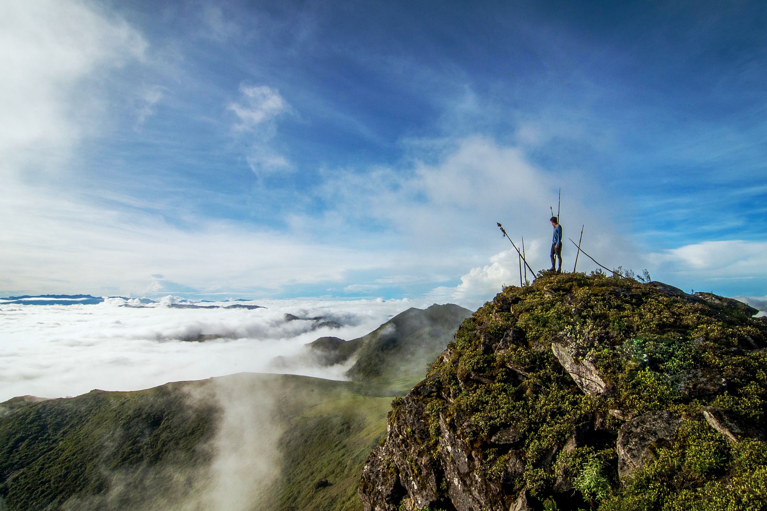 A man stands atop a ledge overlooking the clouds below him in northwestern Bhutan.