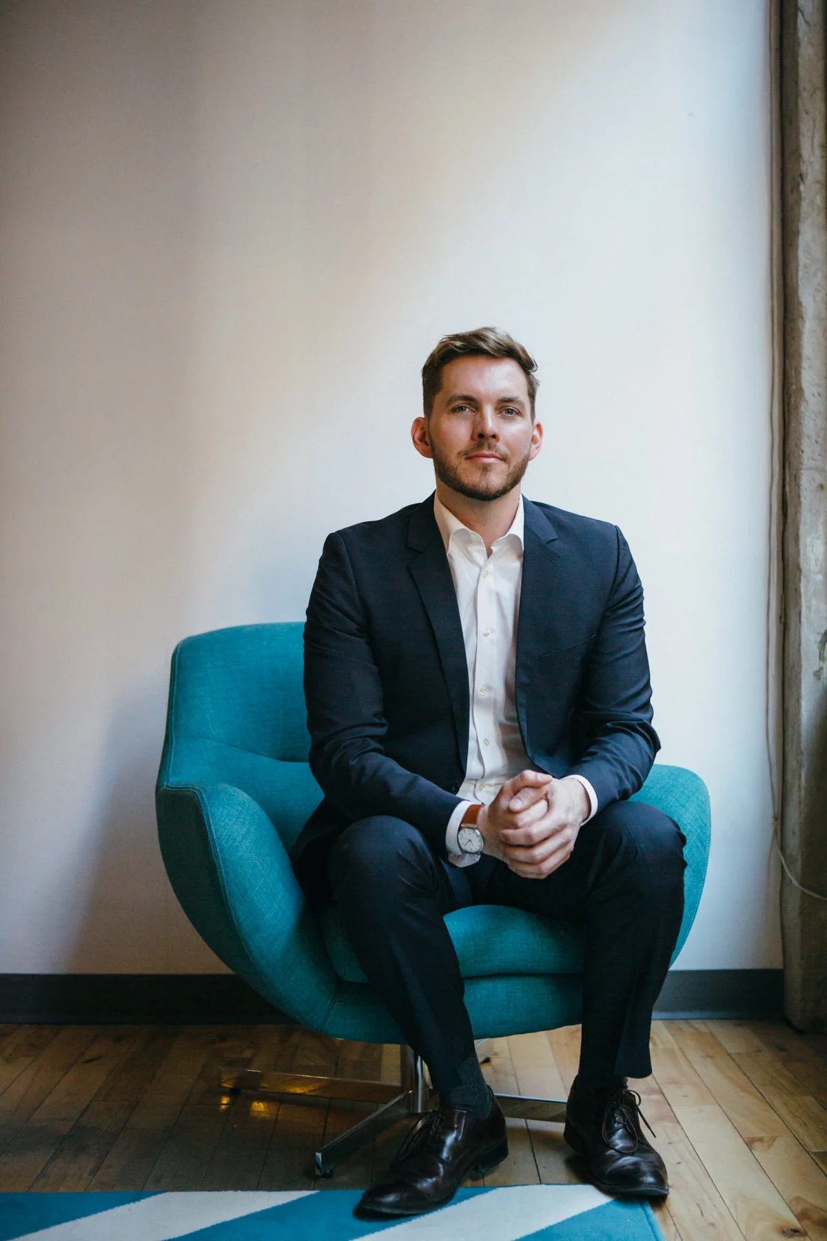Lawyer Marcus McCann sits on blue chair beside window. Photo by Jocelyn Reynonds