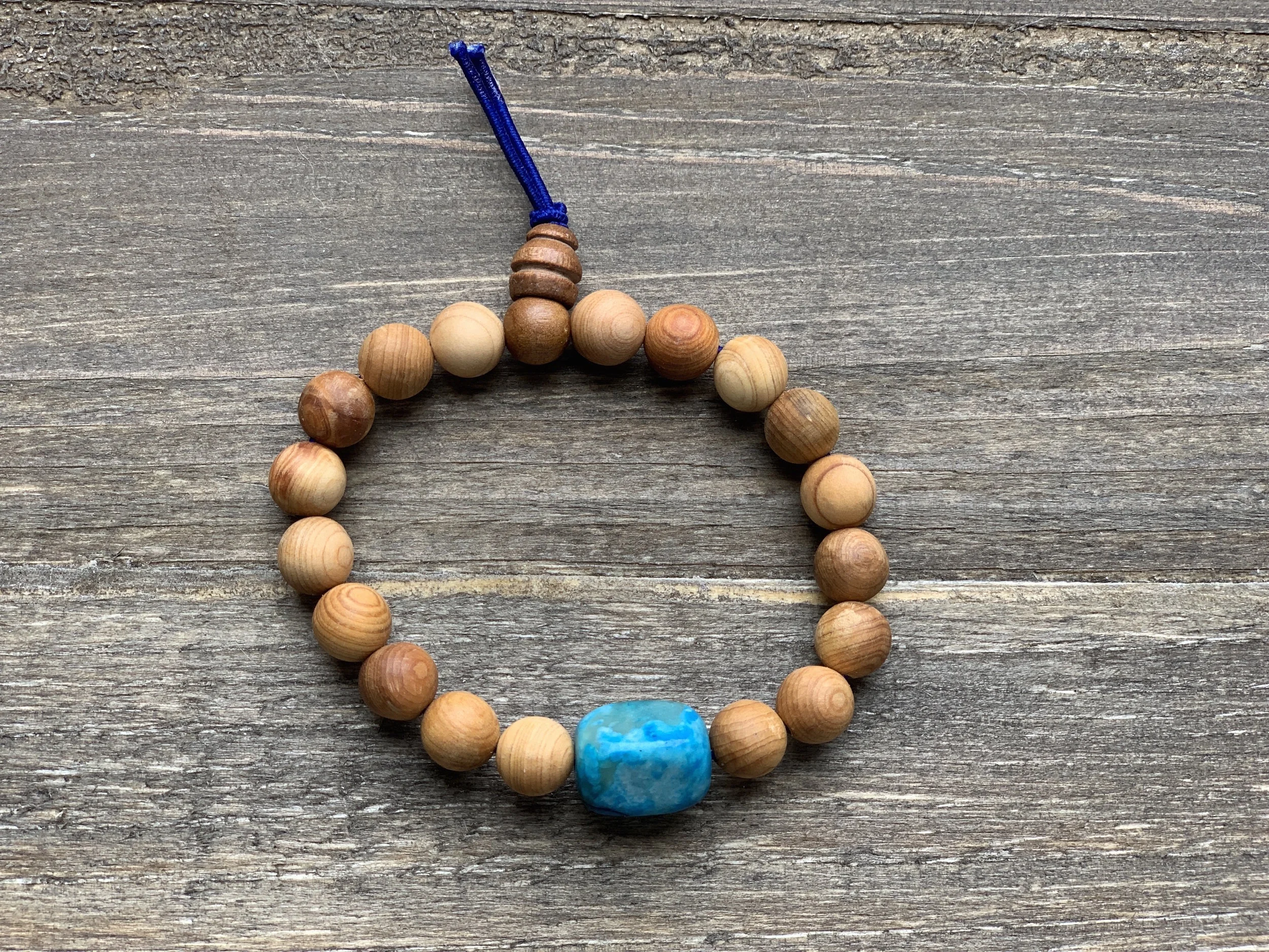 Beaded bracelet with a large turquoise bead on a wood surface.
