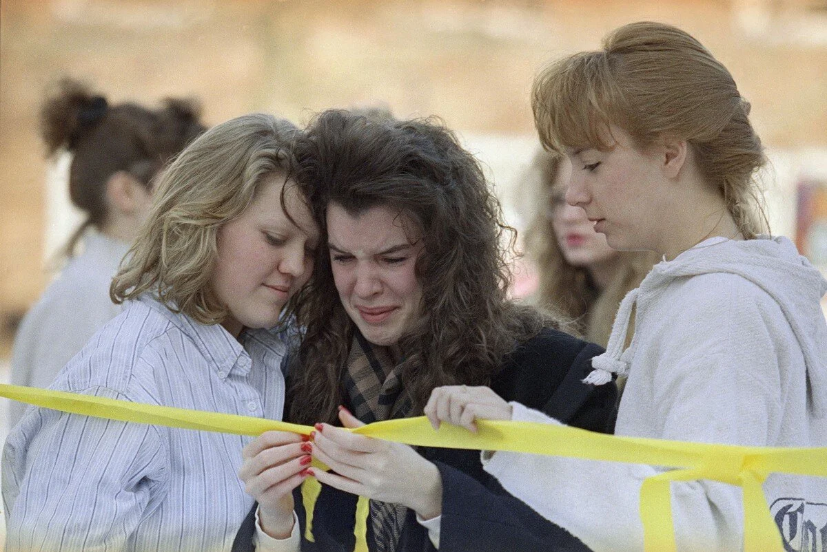 Cazenovia College students Amy Acker, of Rochester, left, and Sandra Ceplo, of Afton, comfort a tearful Megan Murray, of Mechanicville, center, while placing yellow bows and ribbons on campus in Cazenovia, New York, on January 15, 1991. Scores of st…