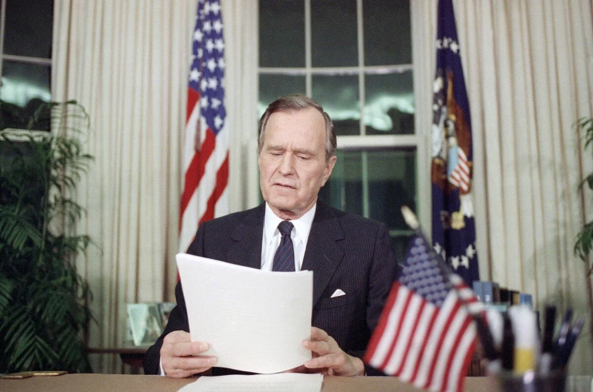 U.S. President George H. W. Bush adjusts paperwork in the Oval Office of the White House on January 16, 1991 in Washington following his statement concerning the U.S. attack of Iraq. The president said, “The world could wait no longer,” for U.S. act…