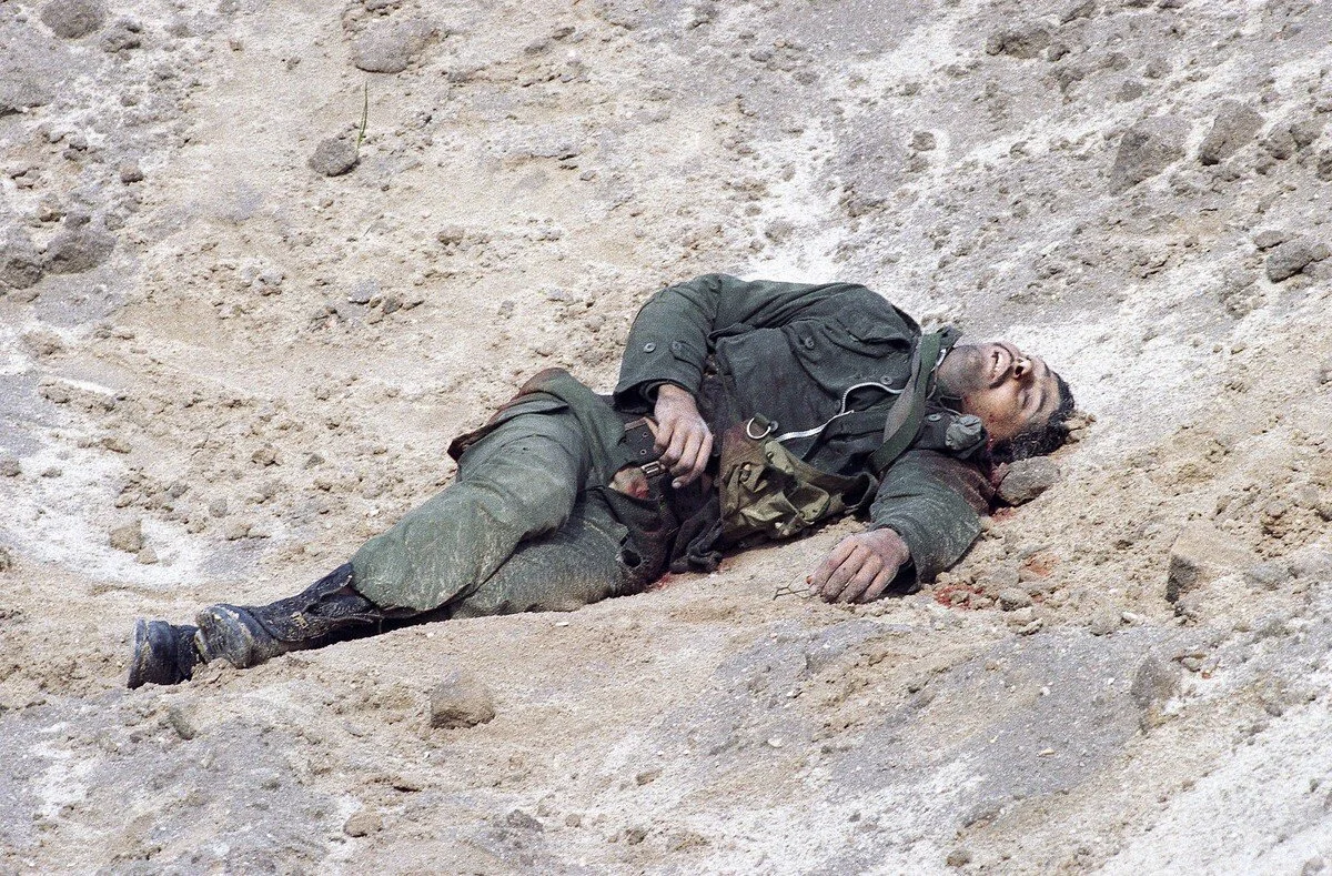 The body of an Iraqi soldier lies in a sandy ditch on the outskirts of Kuwait City on February 27, 1991, after being killed as coalition forces moved in to liberate the city. Laurent Rebours / AP