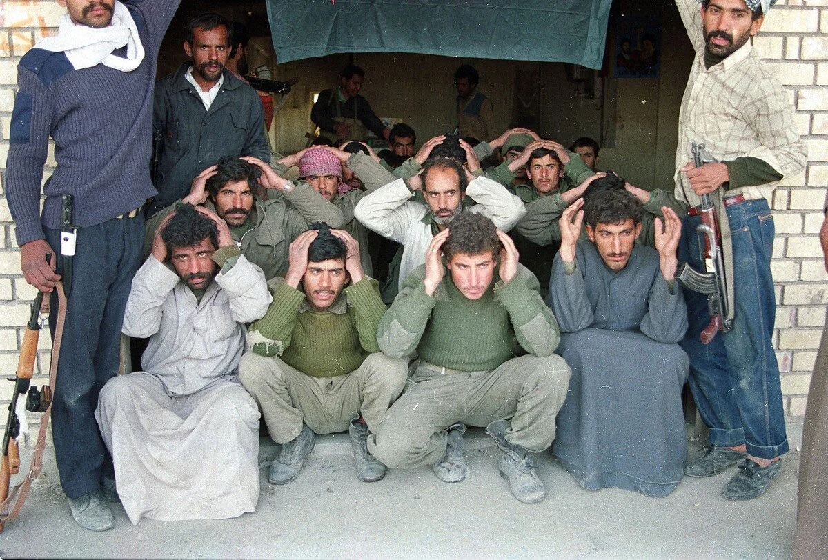 Residents of Tanuma in the Iraqi province of Basra stand guard over captured Iraqi military personnel in March of 1991. AP
