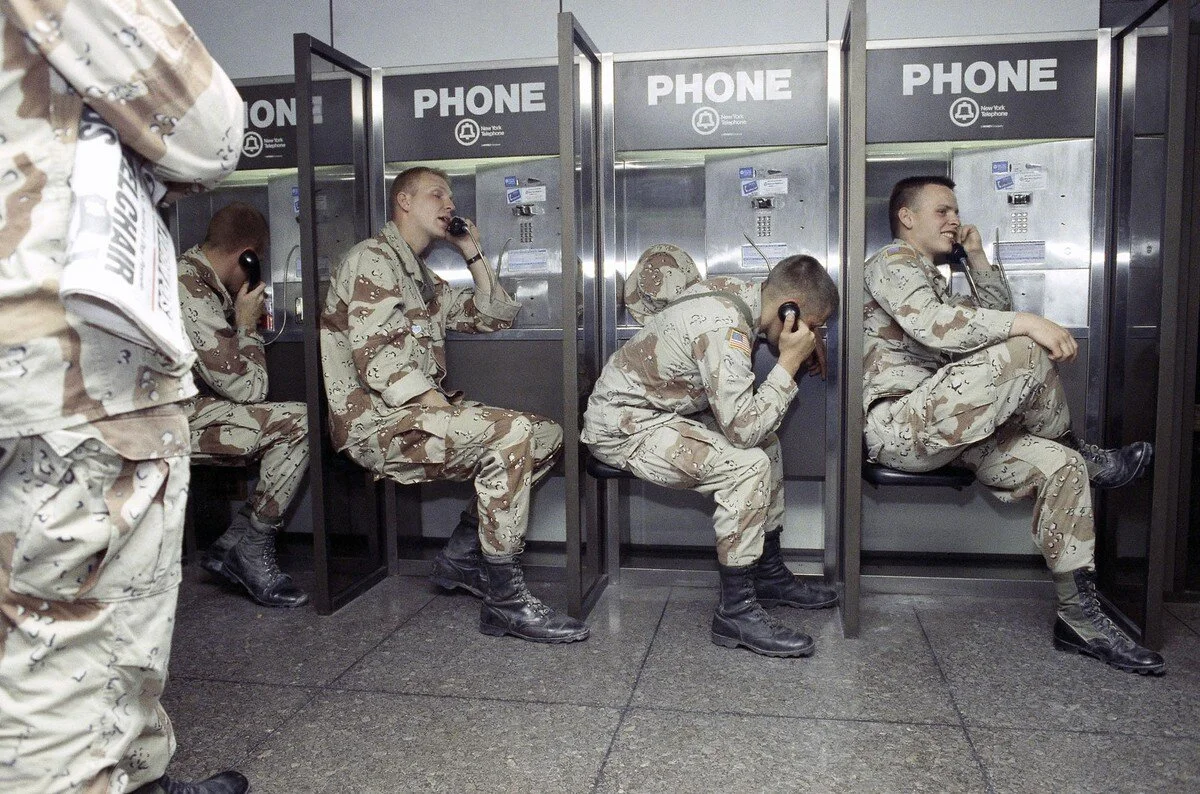 U.S. soldiers returning from the Gulf make telephone calls at New York's Kennedy Airport on March 8, 1991. The soldiers, tired after their 14-hour flight via Rome, flashed “victory” signs as they stepped off planes to the sound of cheering airline e…