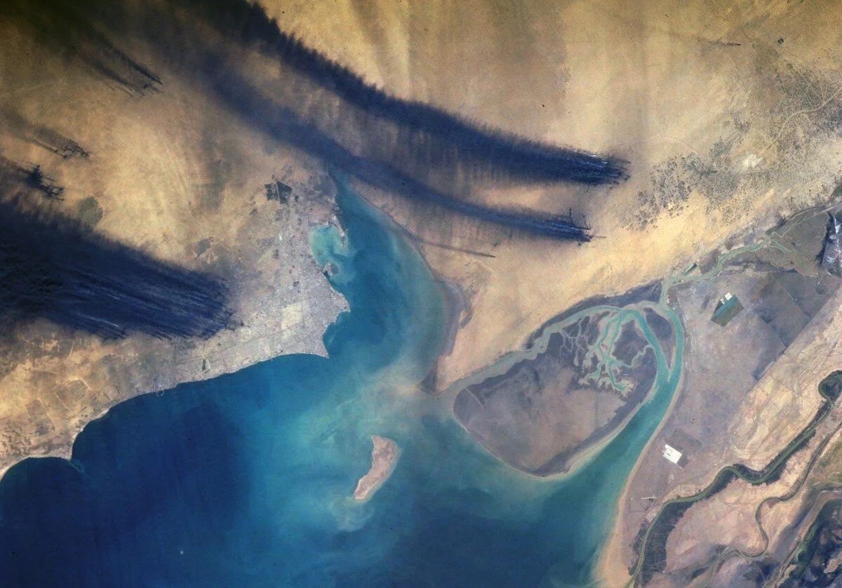 The effects of Iraqi troops setting fire to the oil wells in Kuwait during February 1991, is captured in this near-vertical photograph of the northwestern end of the Persian Gulf taken on April 7, 1991. The black smoke plumes of more than 700 indivi…