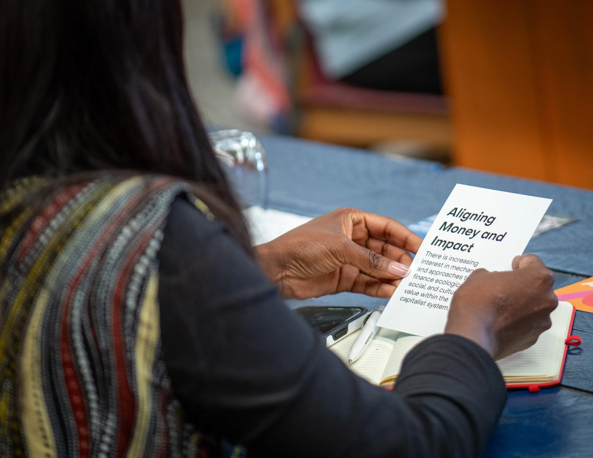 Close up of woman reading a card titled 'Aligning money with impact'