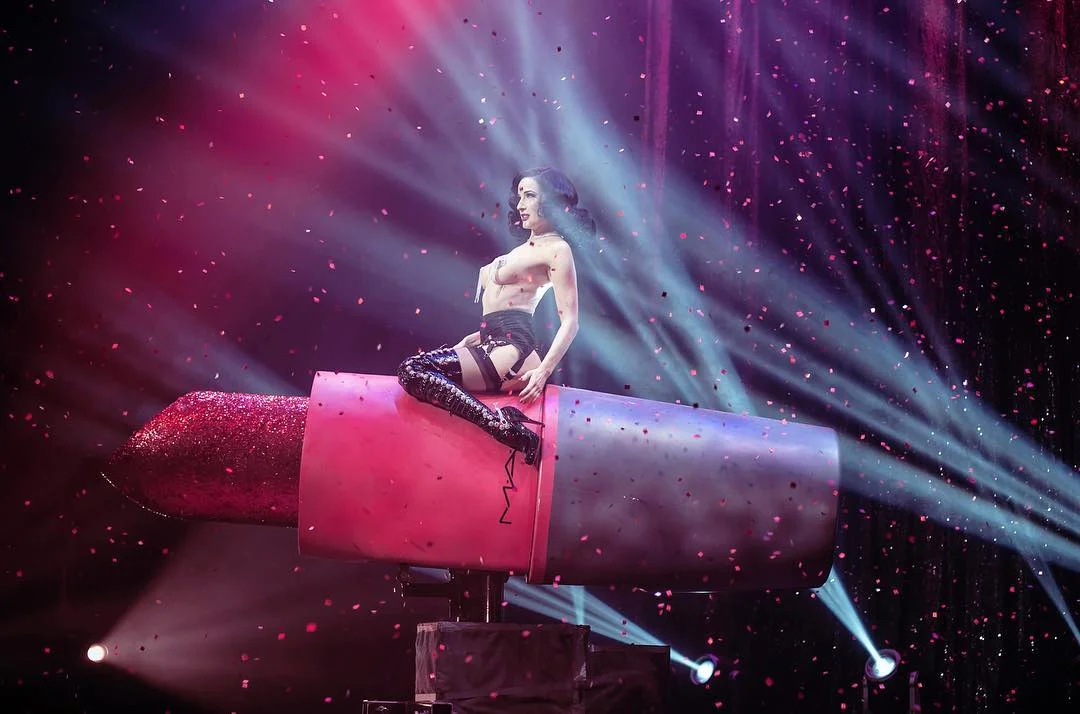 Dita Von Teese rides a giant MAC lipstick during the fetish-themed Lipteese number.