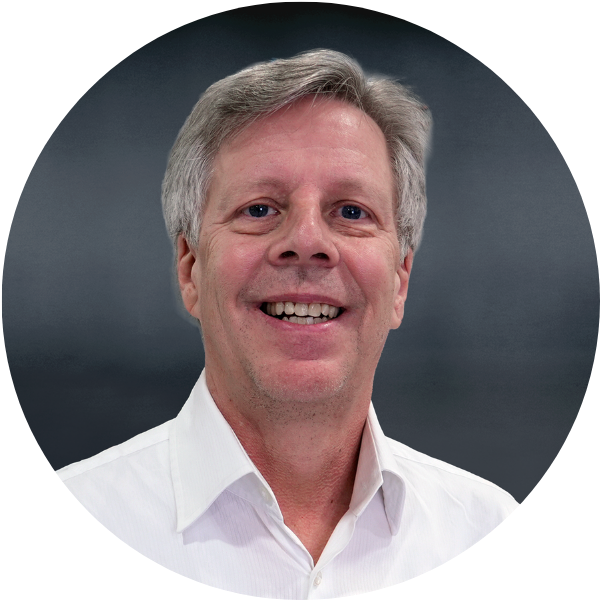 Close-up of a smiling man with gray hair wearing a white collared shirt.
