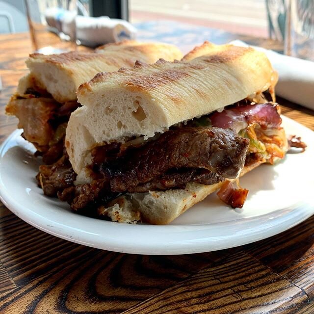 our korean beef cheesesteak is a game changer 💥🤤 bulgogi marinated ribeye, sautéed peppers and onions, grilled kimchi, white cheddar and garlic aioli on a french baguette. order one now at the link in our bio!