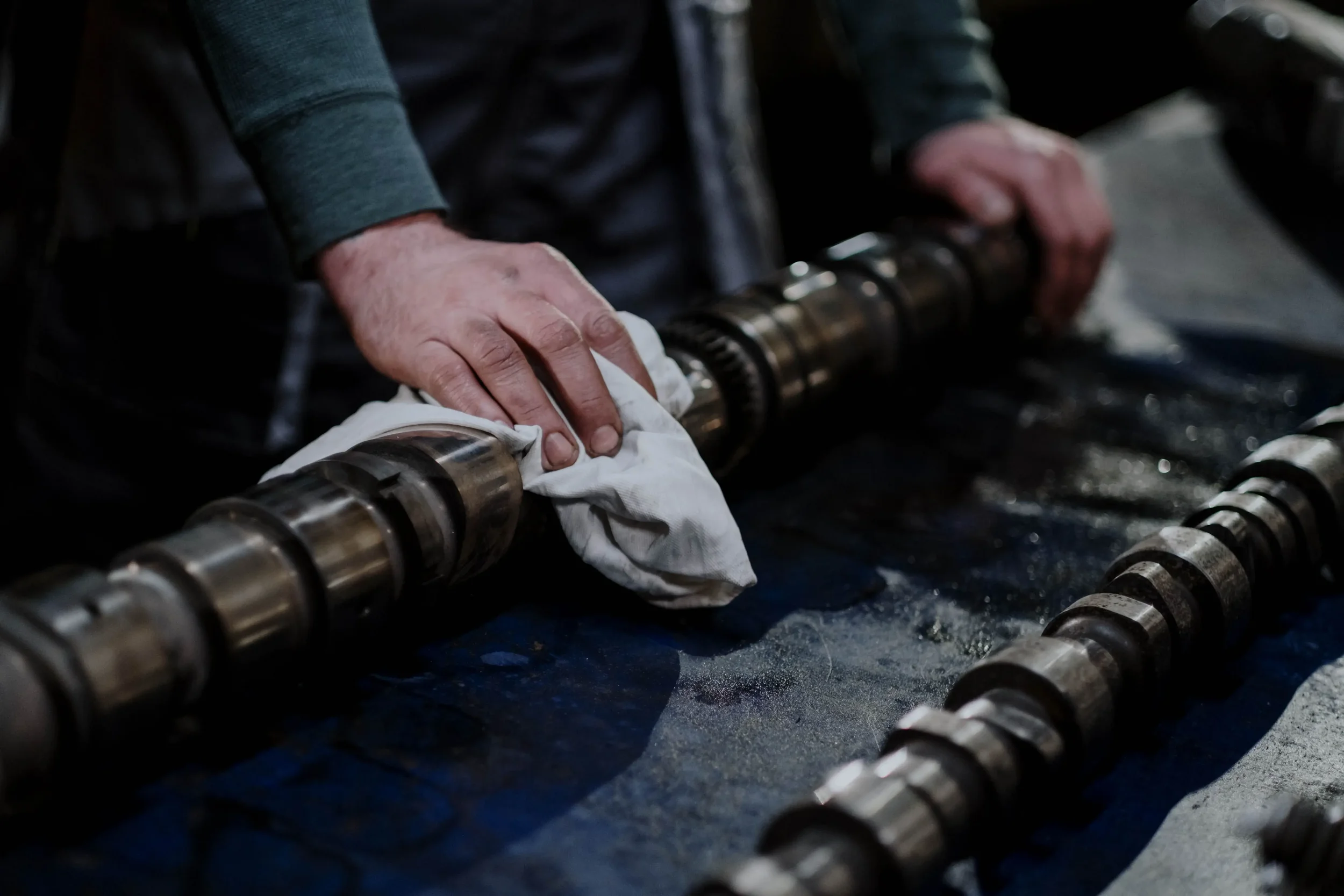 A Man Carefully Uses a White Rag to Apply Grease to a Metal Surface to Avoid Overgreasing It.