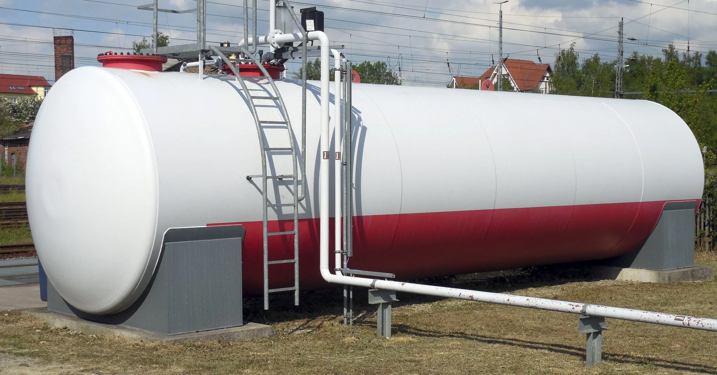 Large horizontal aboveground bulk fuel storage tank with access ladder and external piping.