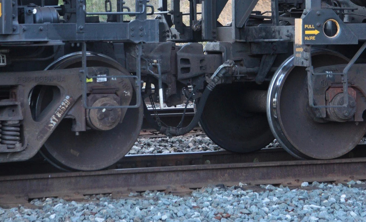 Close-up view of steel railroad wheels and undercarriage components on the track.