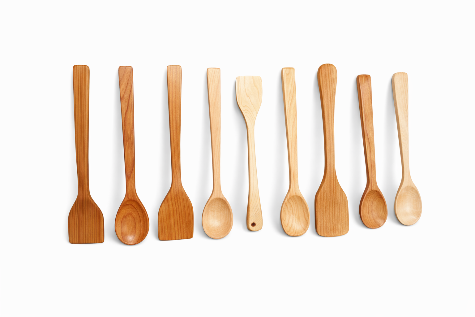 Nine wooden kitchen utensils arranged in a row on a white background, including spatulas and spoons.