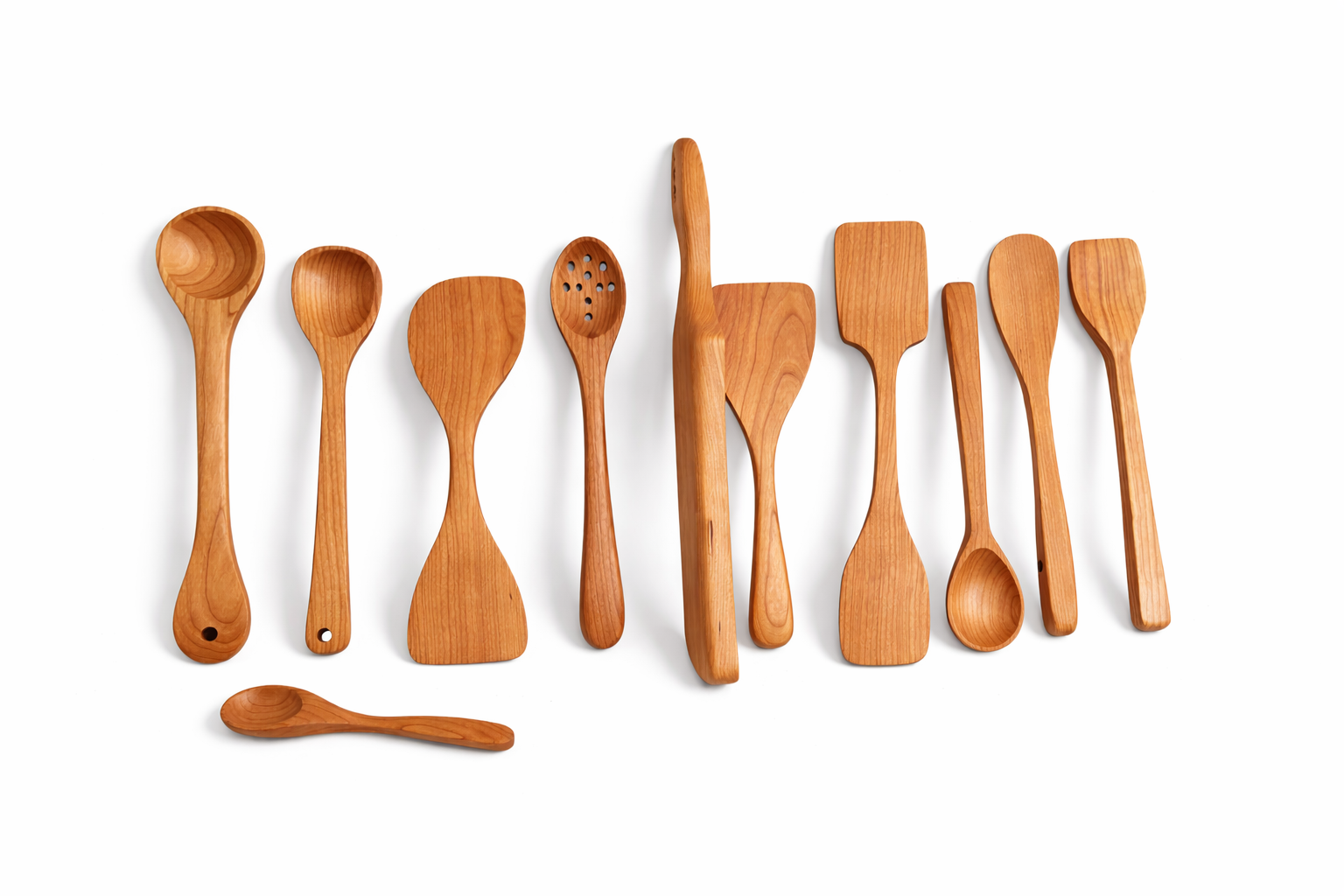 A set of ten wooden cooking spoons on a white surface, with a small wooden spoon in front.