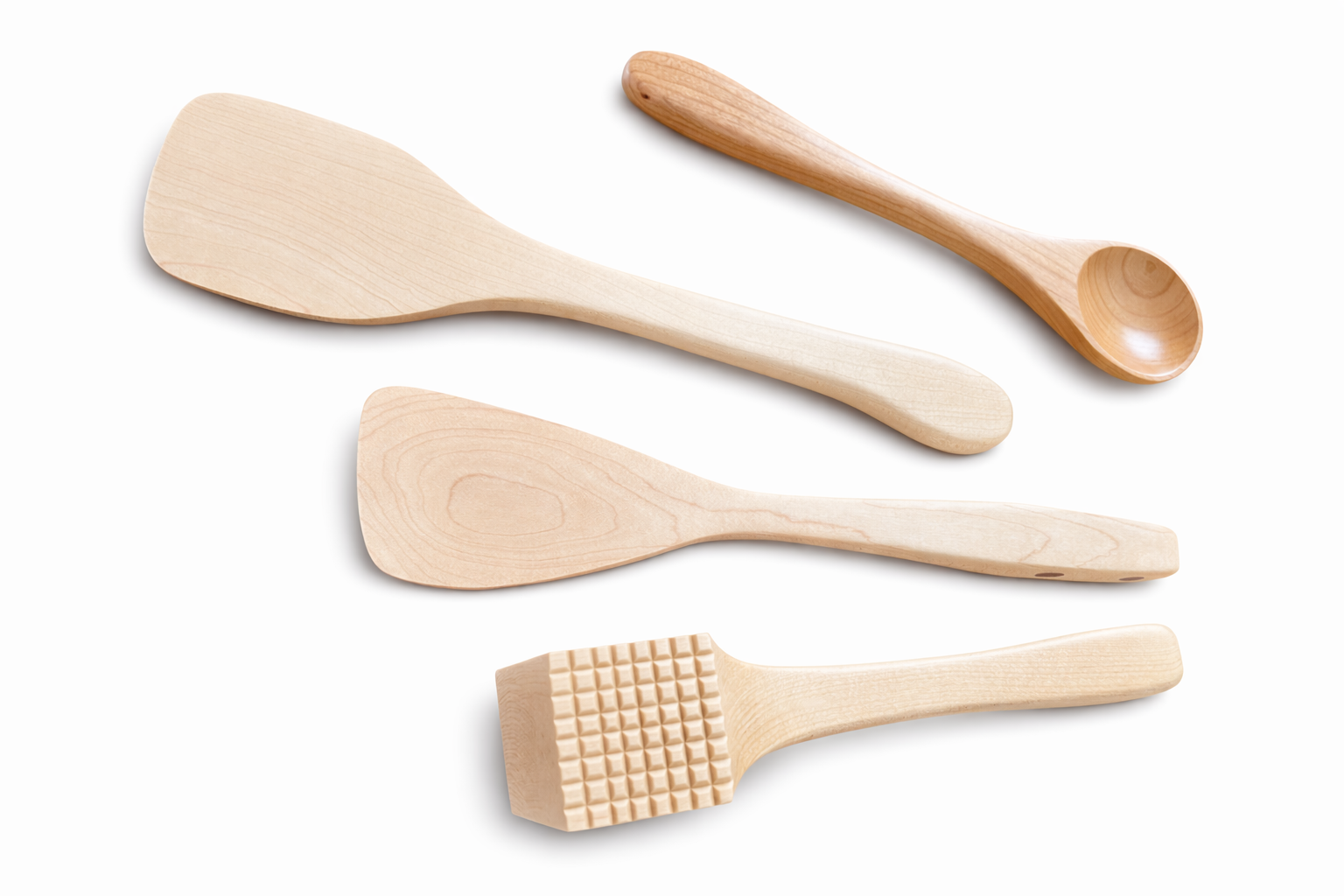 Set of four wooden kitchen utensils, including a wide spatula, a slender spoon, a rounded spatula, and a square-ended textured spatula, arranged on a white background.