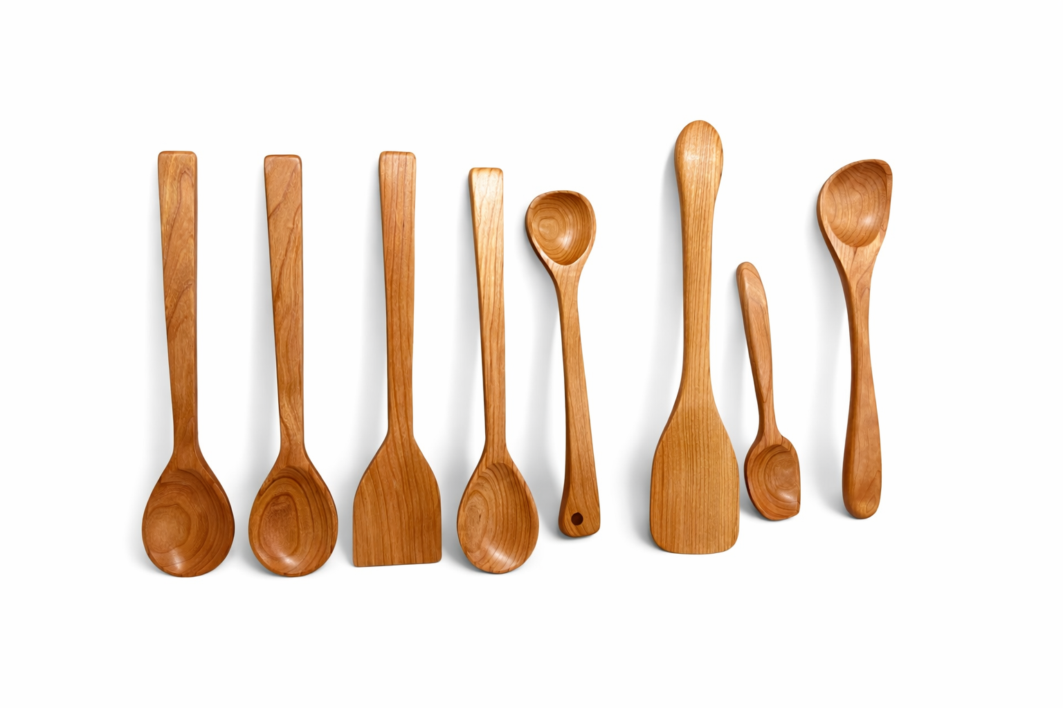 Eight wooden kitchen utensils, including spoons and spatulas, are arranged in a row on a white background.