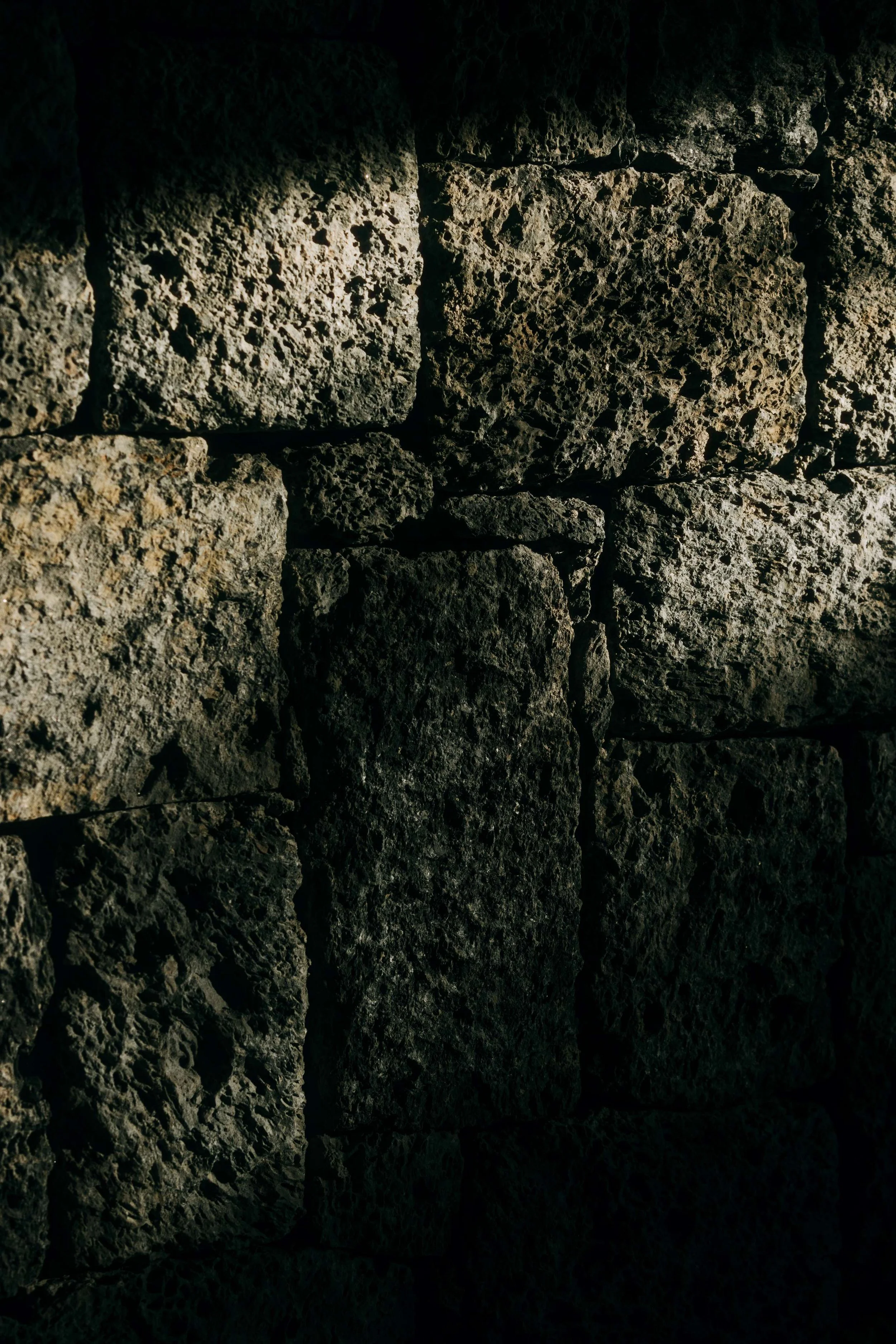 Close-up of hand-hewn volcanic rock wall inside Bisate Sanctuary, showing the raw texture and craftsmanship of locally sourced stone — Black Sable