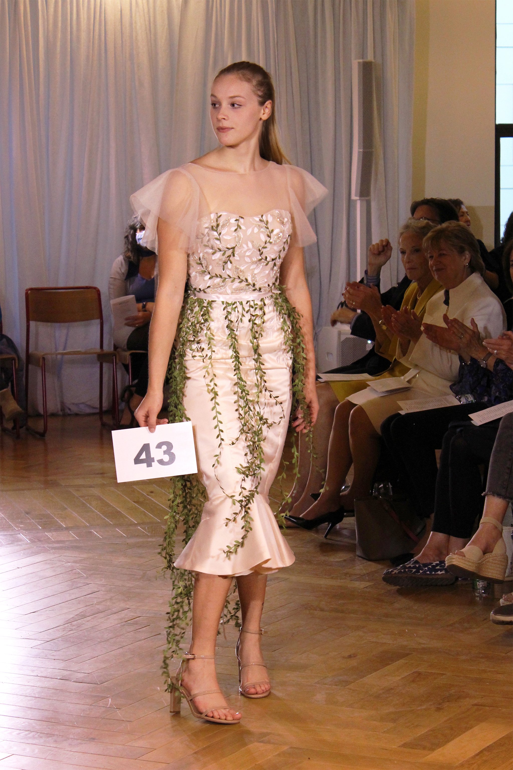 Model wearing shin-length dress with a flower and vine detail overlay.