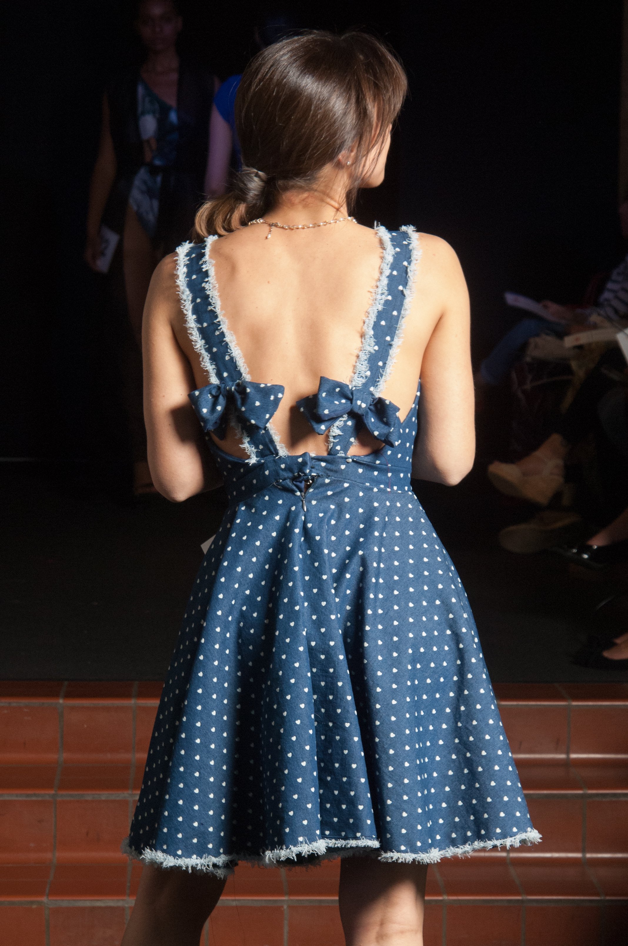 Model wearing blue dress with white dots.