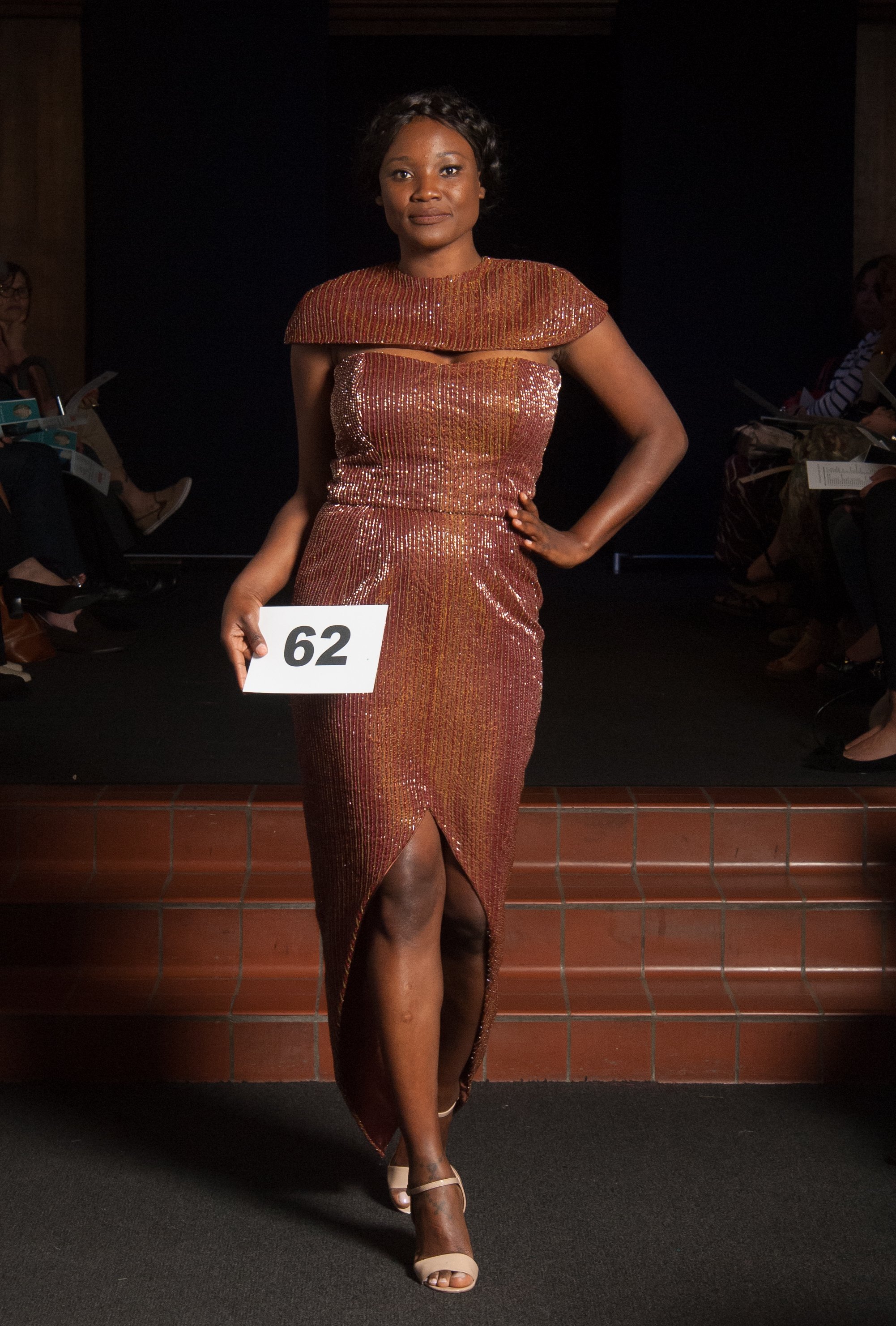 Model wearing brown strapless dress with shoulder cape.