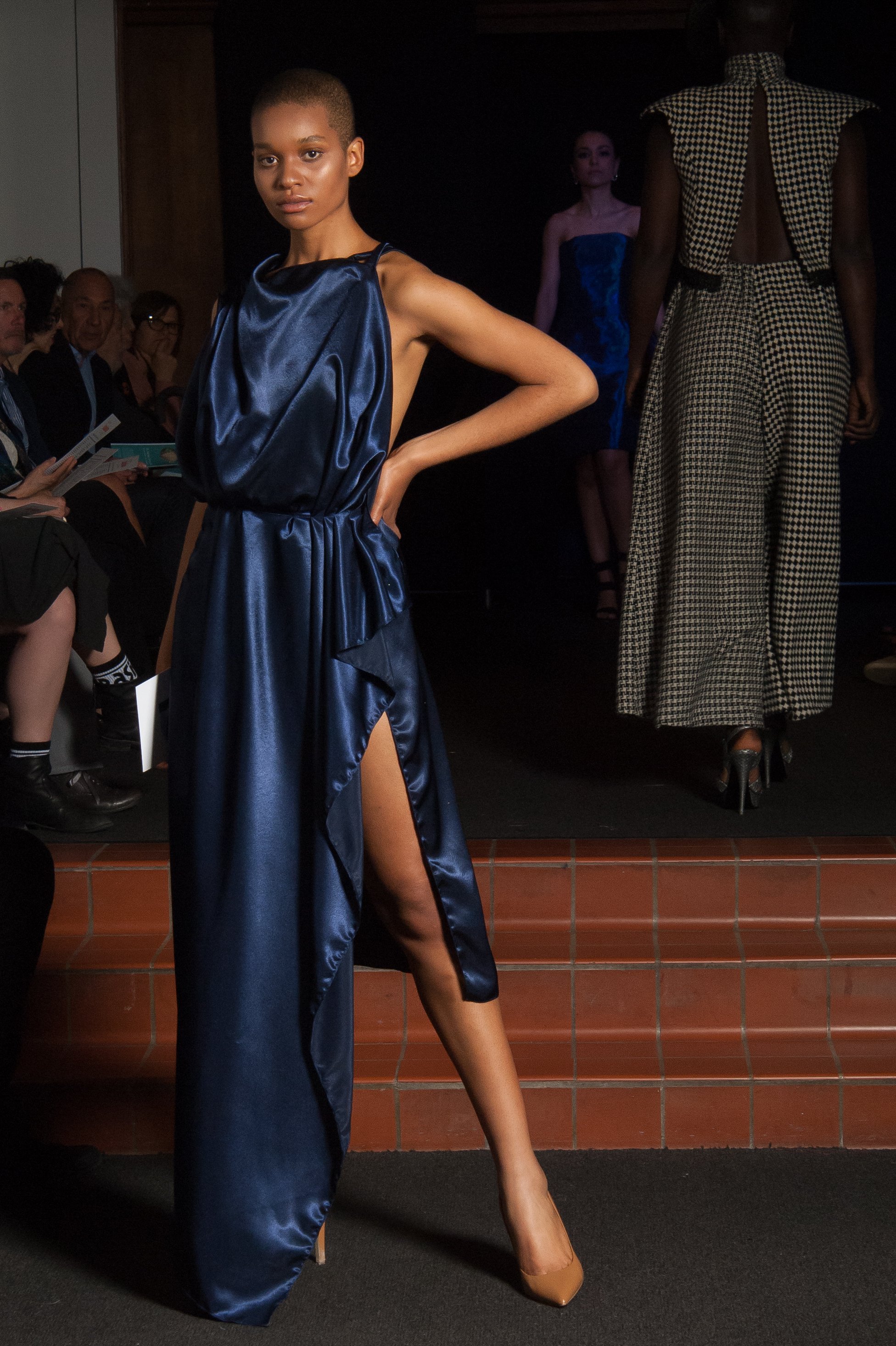 Model wearing navy blue floor length dress with mid-thigh slit on the side.