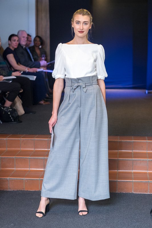 Model wearing white 3/4 length blouse with wide-leg grey pants.