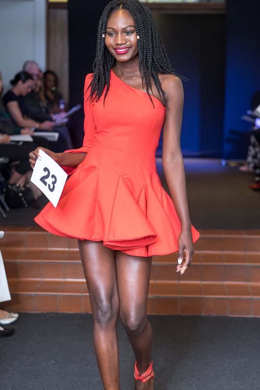 Model wearing one shoulder, mid-thigh length, coral dress