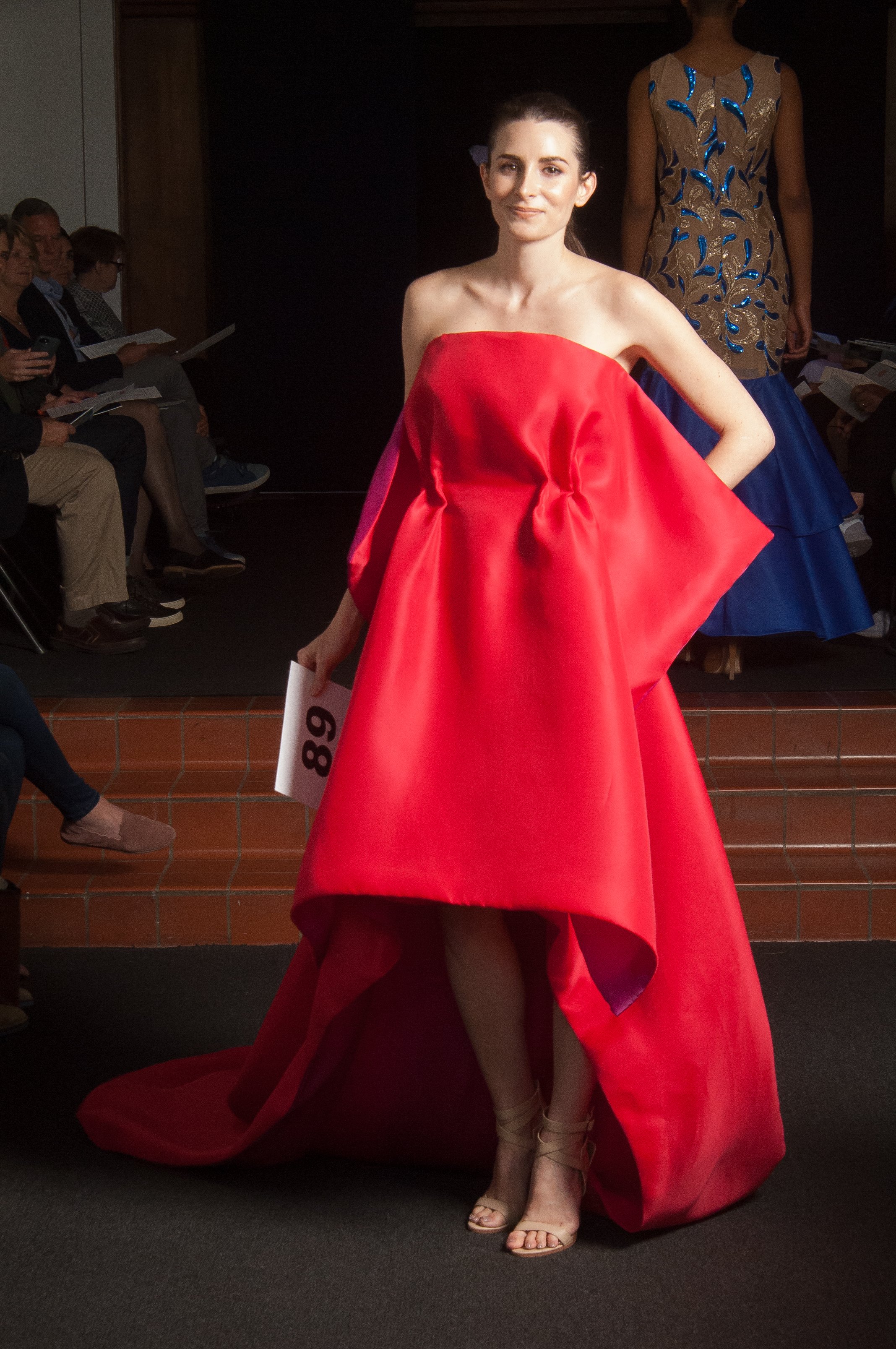 Model wearing bright red, strapless, high-low dress.