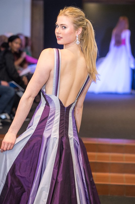 Model wearing long evening dress with different variations of purplpe stripes.