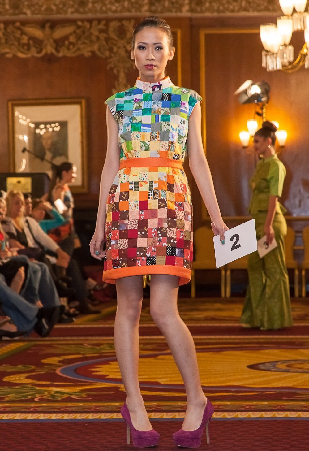 Model wearing multi-colored, knee length, quilted dress. 