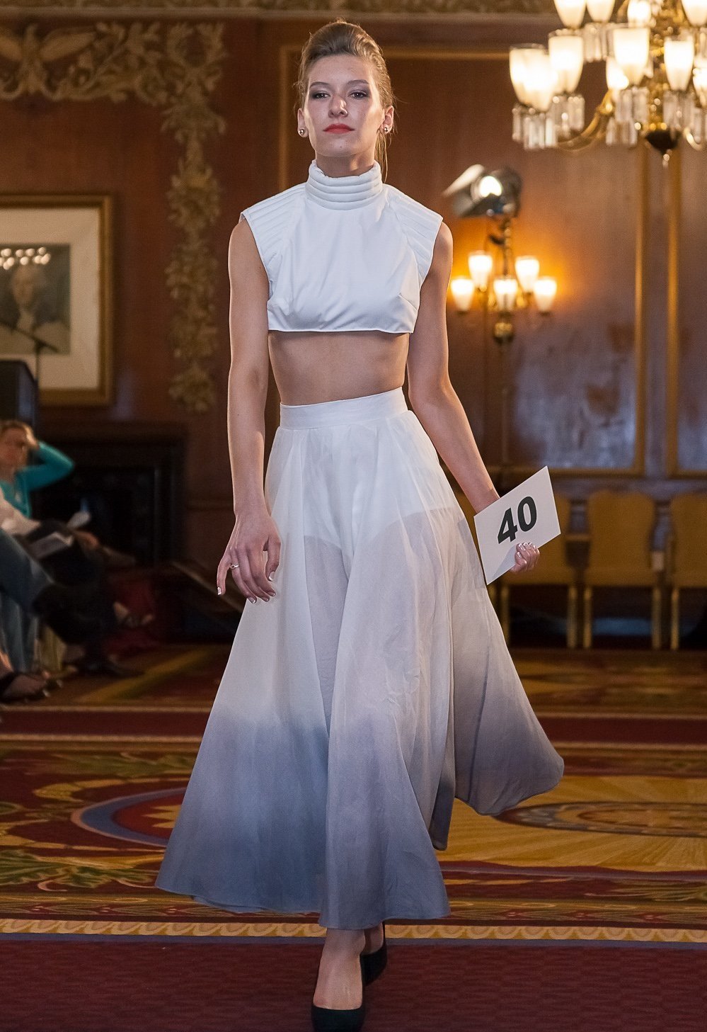 Model wearing two-piece matching set.  Top is white short sleeved, mock neck, cropped.  Along with ankle length skirt that is white to blue ombre.