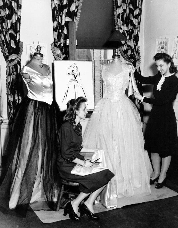 Two students pose with their final garments and sketches