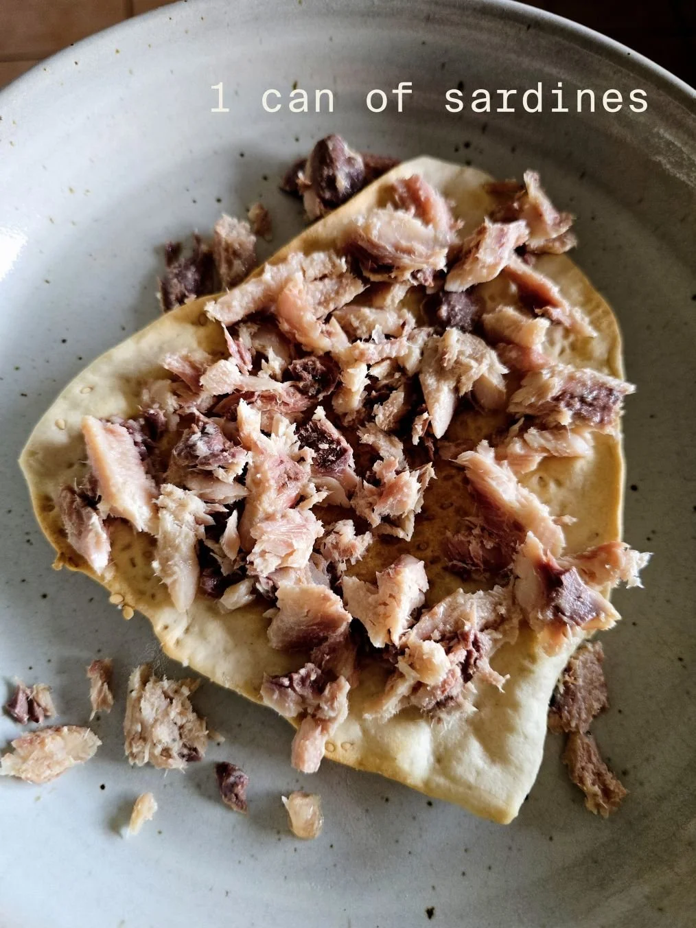 Hand holding a tin of Wild Planet Wild Pacific sardines in extra virgin olive oil, lightly smoked