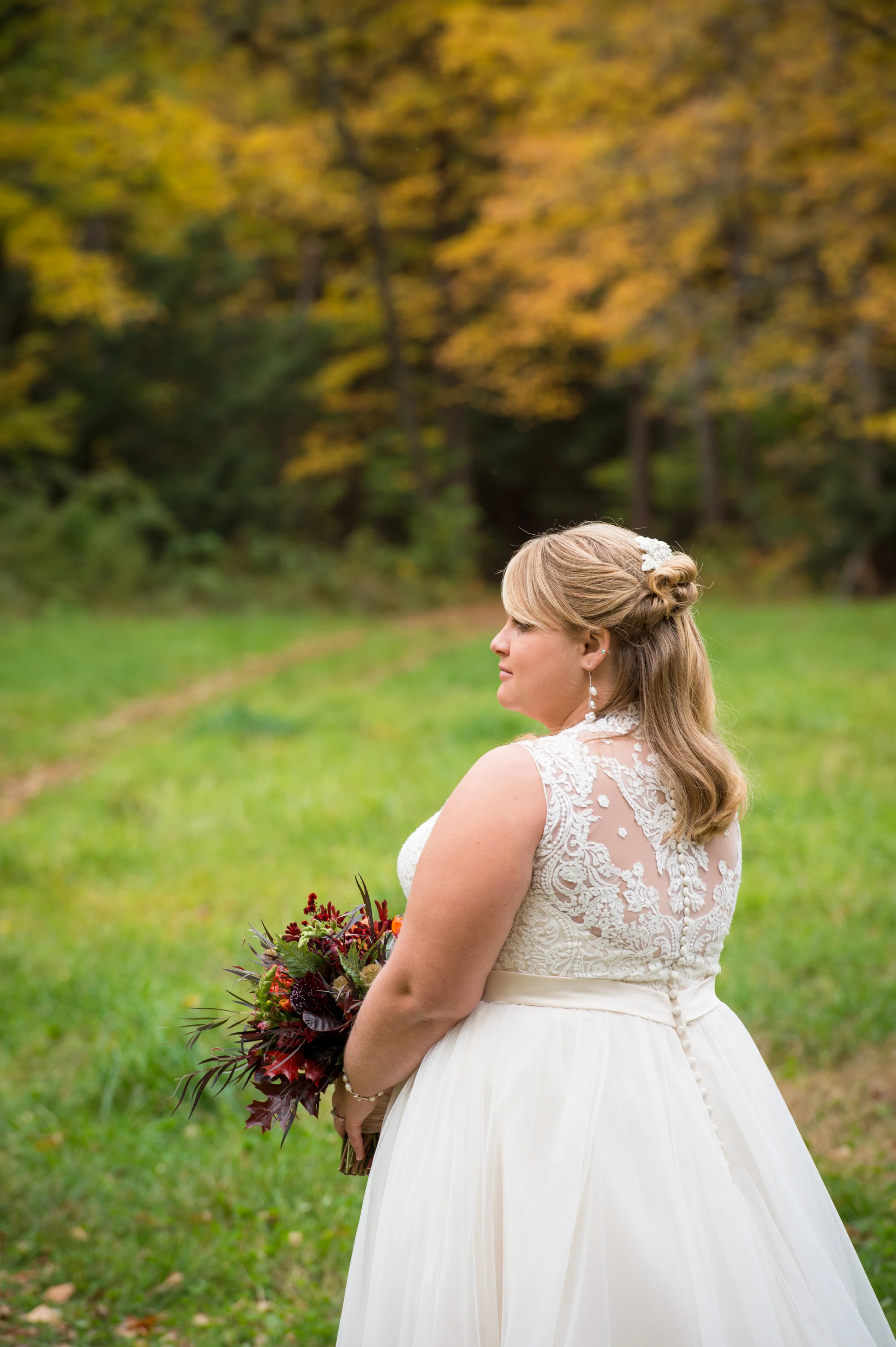 Marrier in wedding dress standing in a field with bouquet during Boston wedding Michelle Schapiro Photography