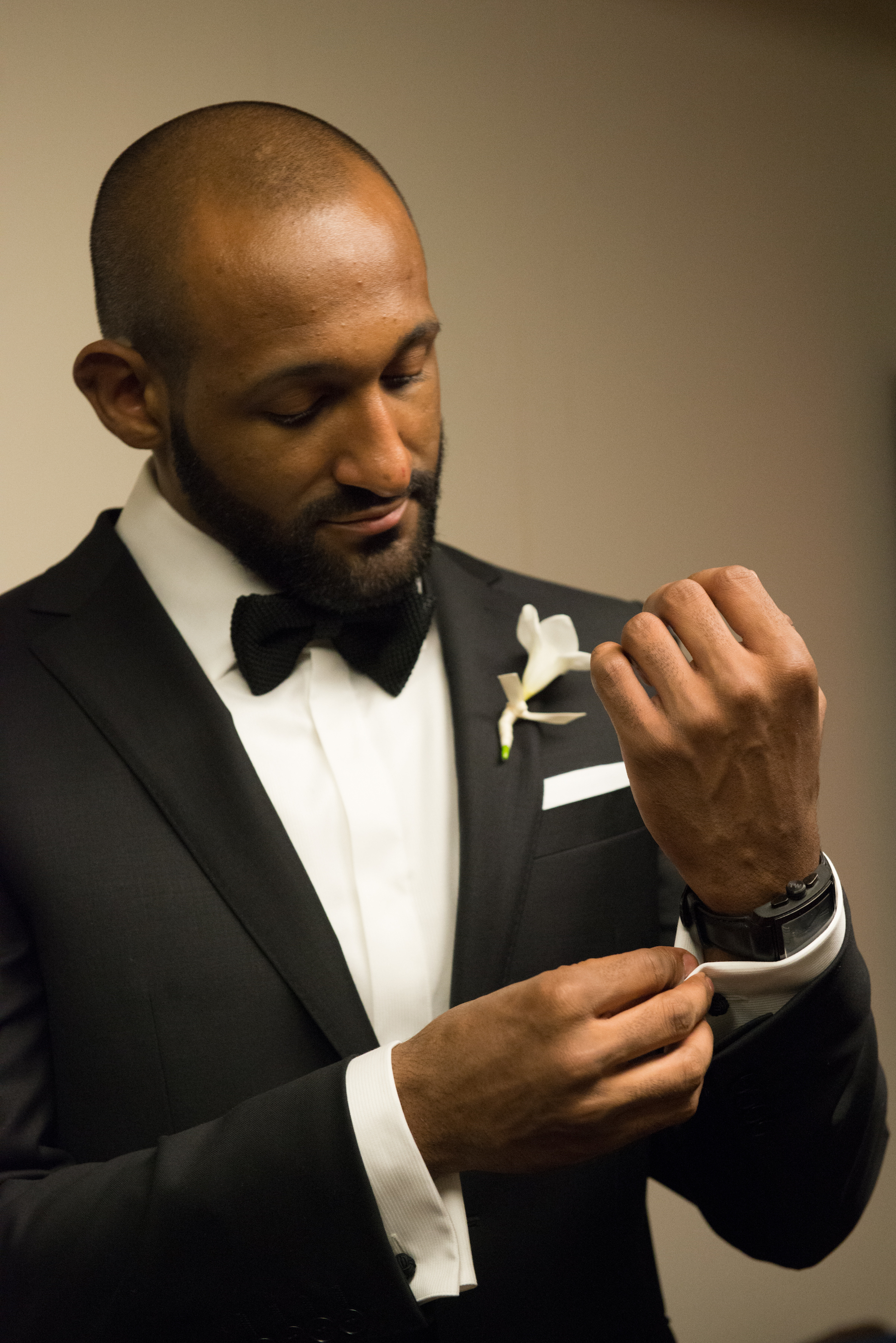 Reggie puts on cufflinks while getting ready in suit before wedding ceremony at MIT Chapel in Boston Massachusetts Michelle Schapiro Photography