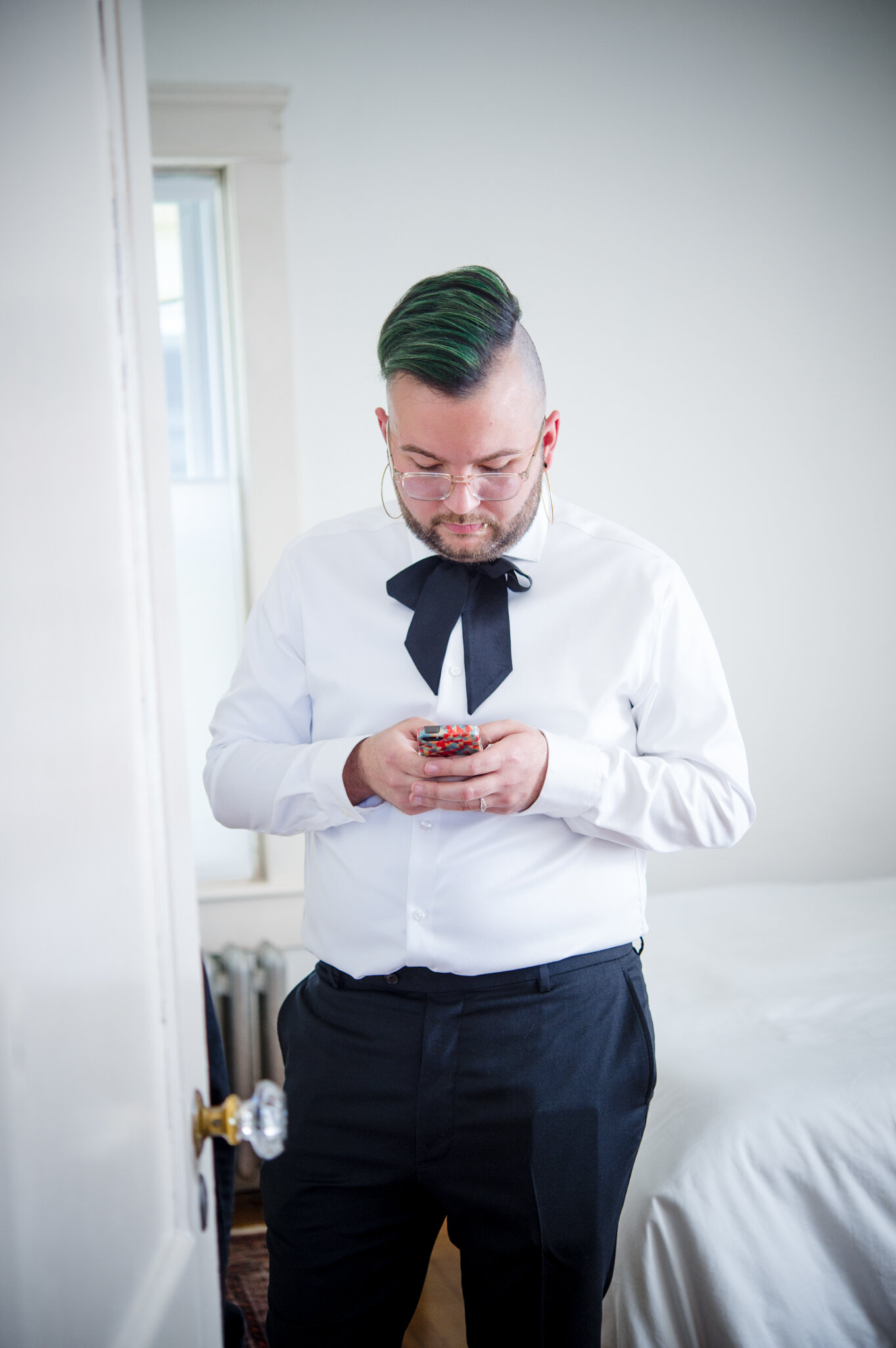 Marrier in white shirt and tie checks phone while getting ready before ceremony at Roger Williams Botanical Center Providence Rhode Island Michelle Schapiro New England Wedding Photographer
