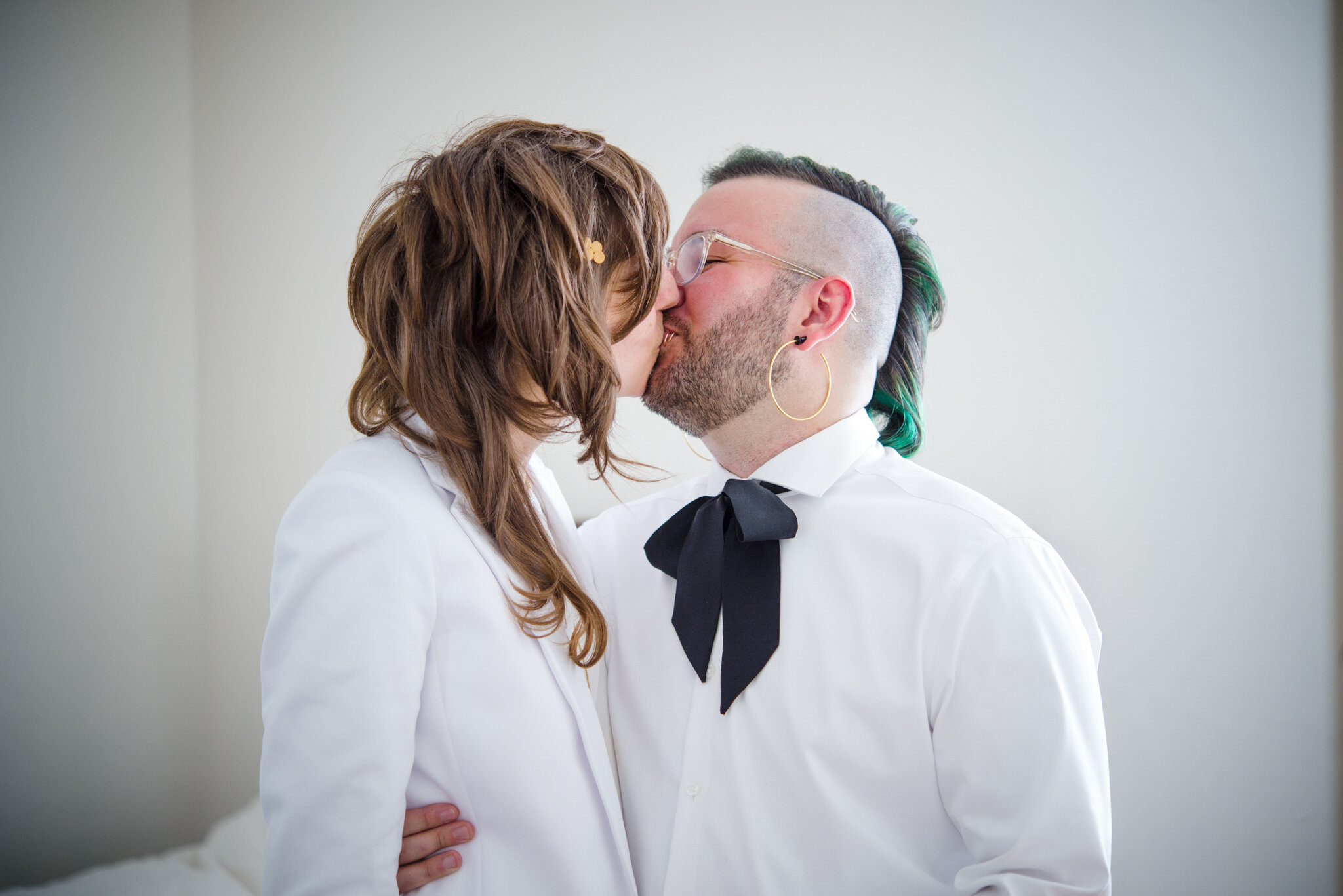 Queer marriers in white suit and white shirt kiss while getting ready before ceremony at Roger Williams Botanical Center Providence Rhode Island Michelle Schapiro New England Wedding Photographer