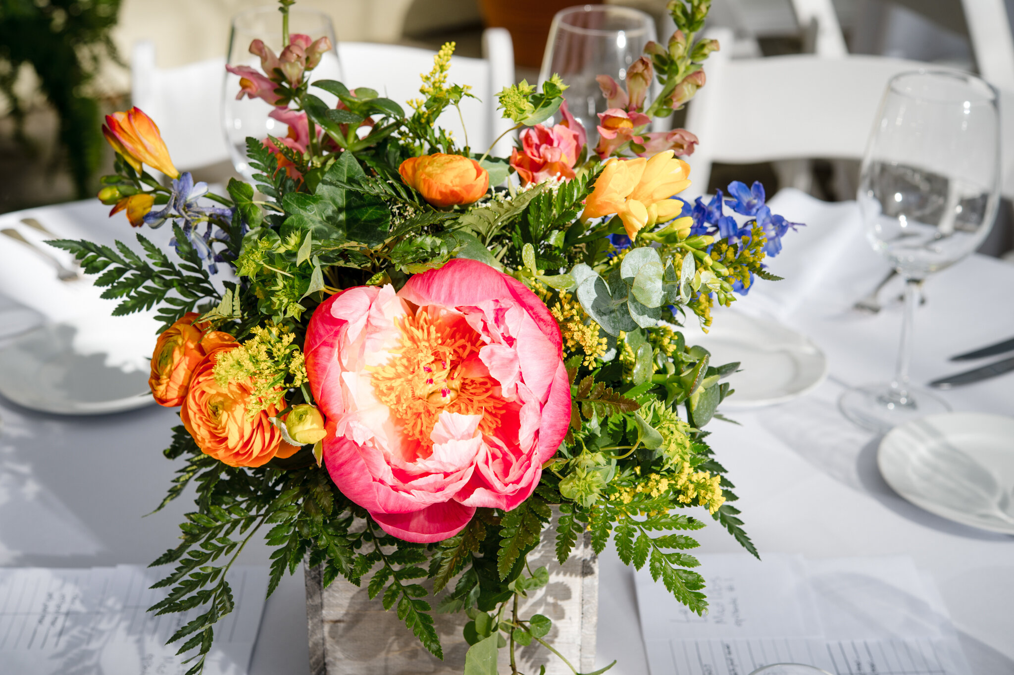 Close up of bright floral centerpiece on guest reception table during queer wedding at Roger Williams Botanical Center Providence Rhode Island Michelle Schapiro New England Portrait Photographer